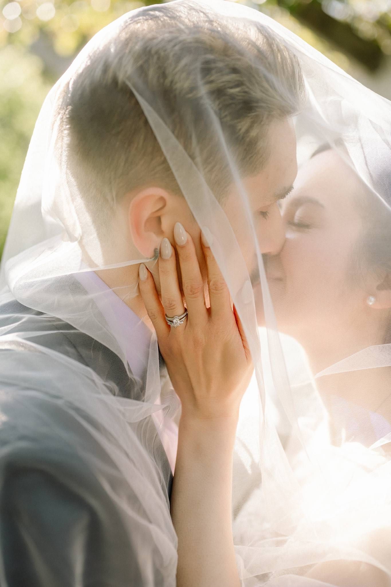 Couple beneath the veil, her hand at his cheek