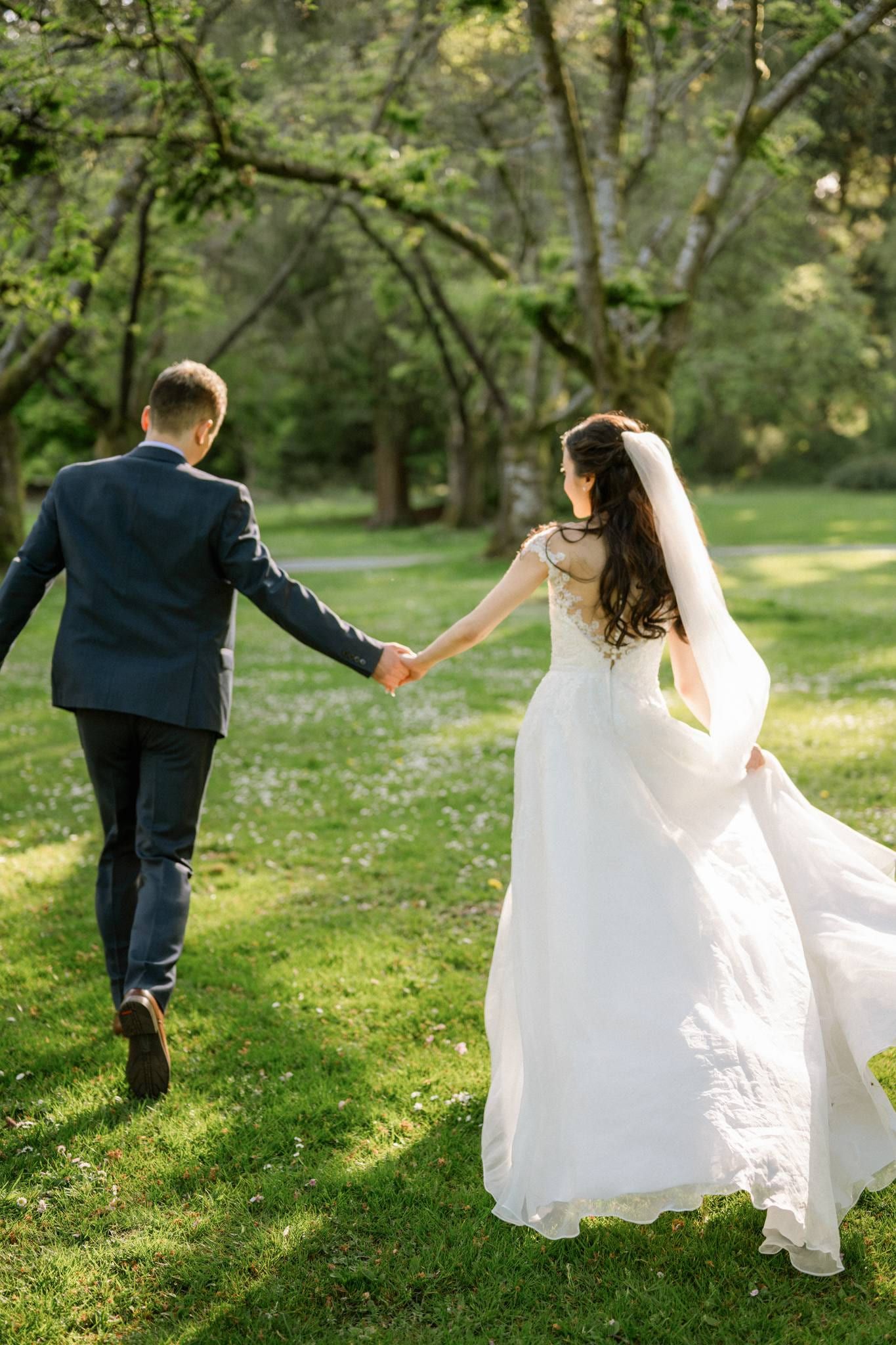 Couple holding hands on the lawn beneath the garden trees