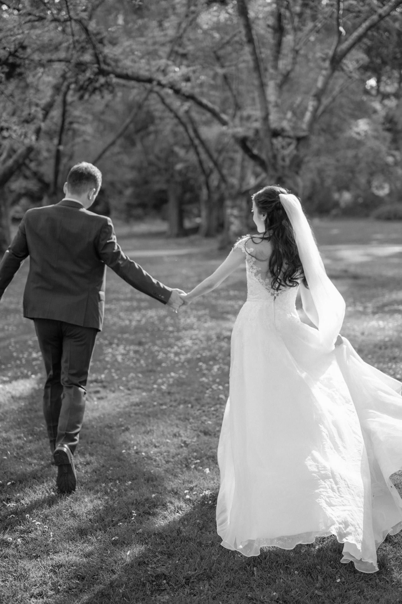 Black-and-white photo of the couple walking hand in hand through the garden