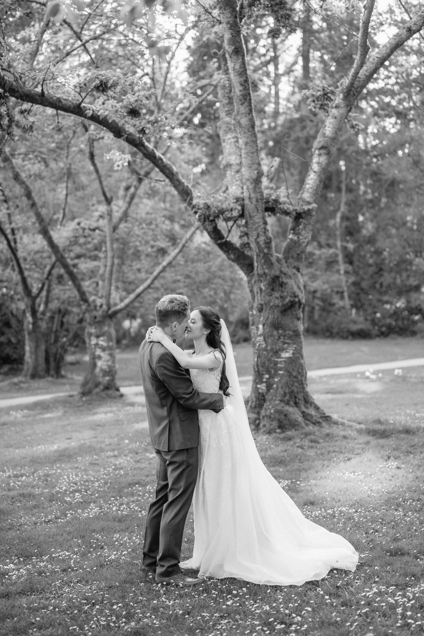 Black-and-white photo of the couple embracing beneath the trees