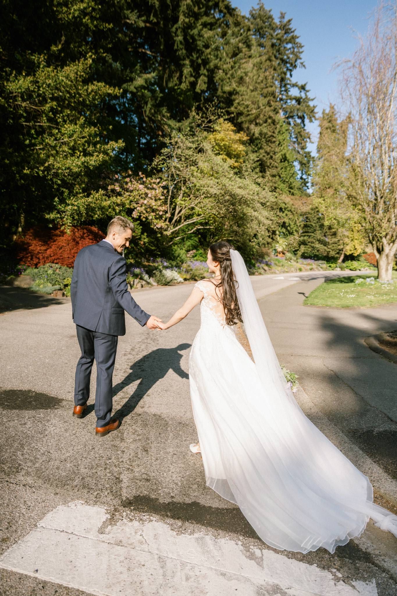 Bride and groom walking a garden path, her train trailing