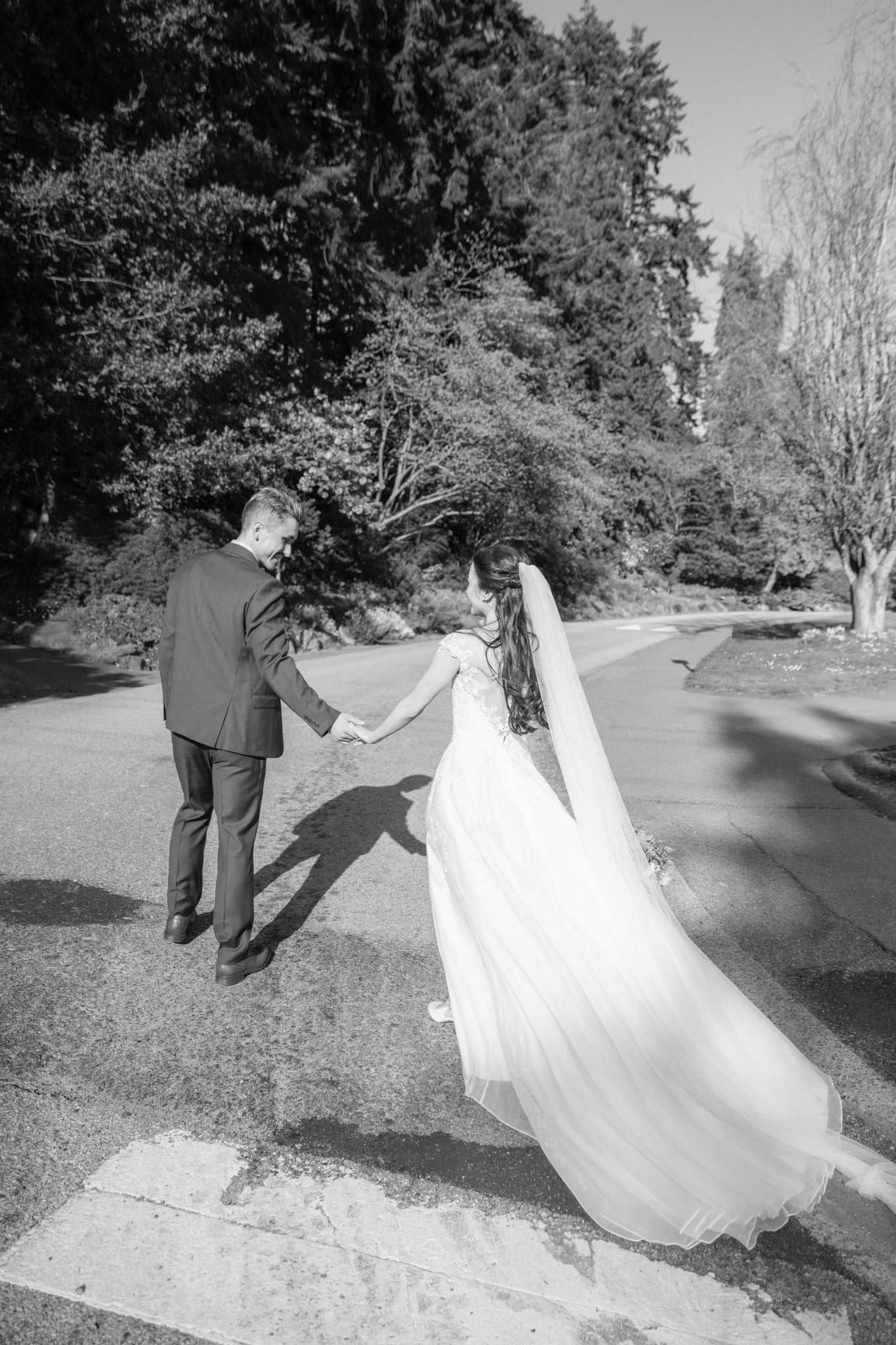 Black-and-white photo of the couple walking hand in hand on the garden path