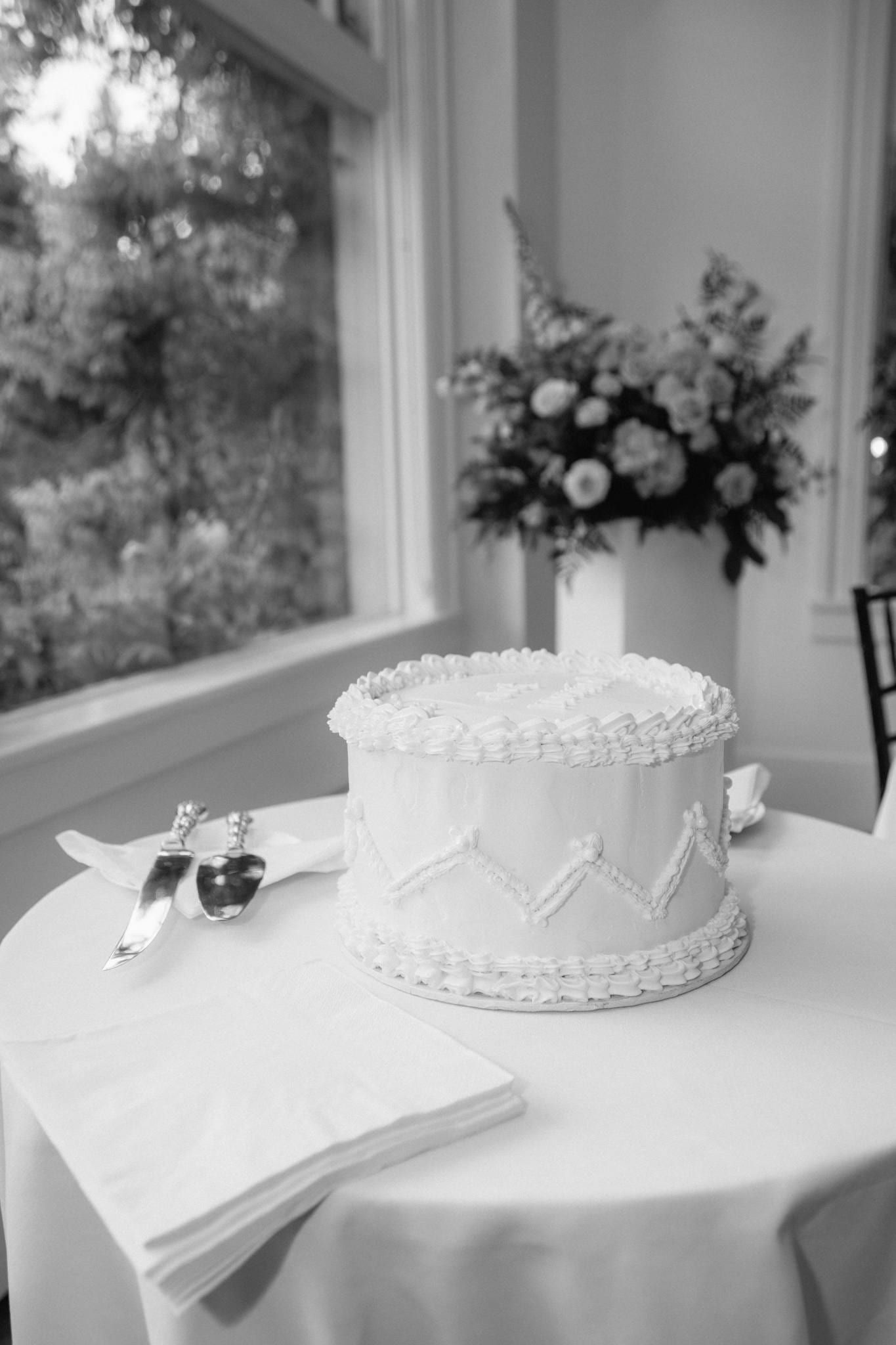 White wedding cake and flowers on a table by the window