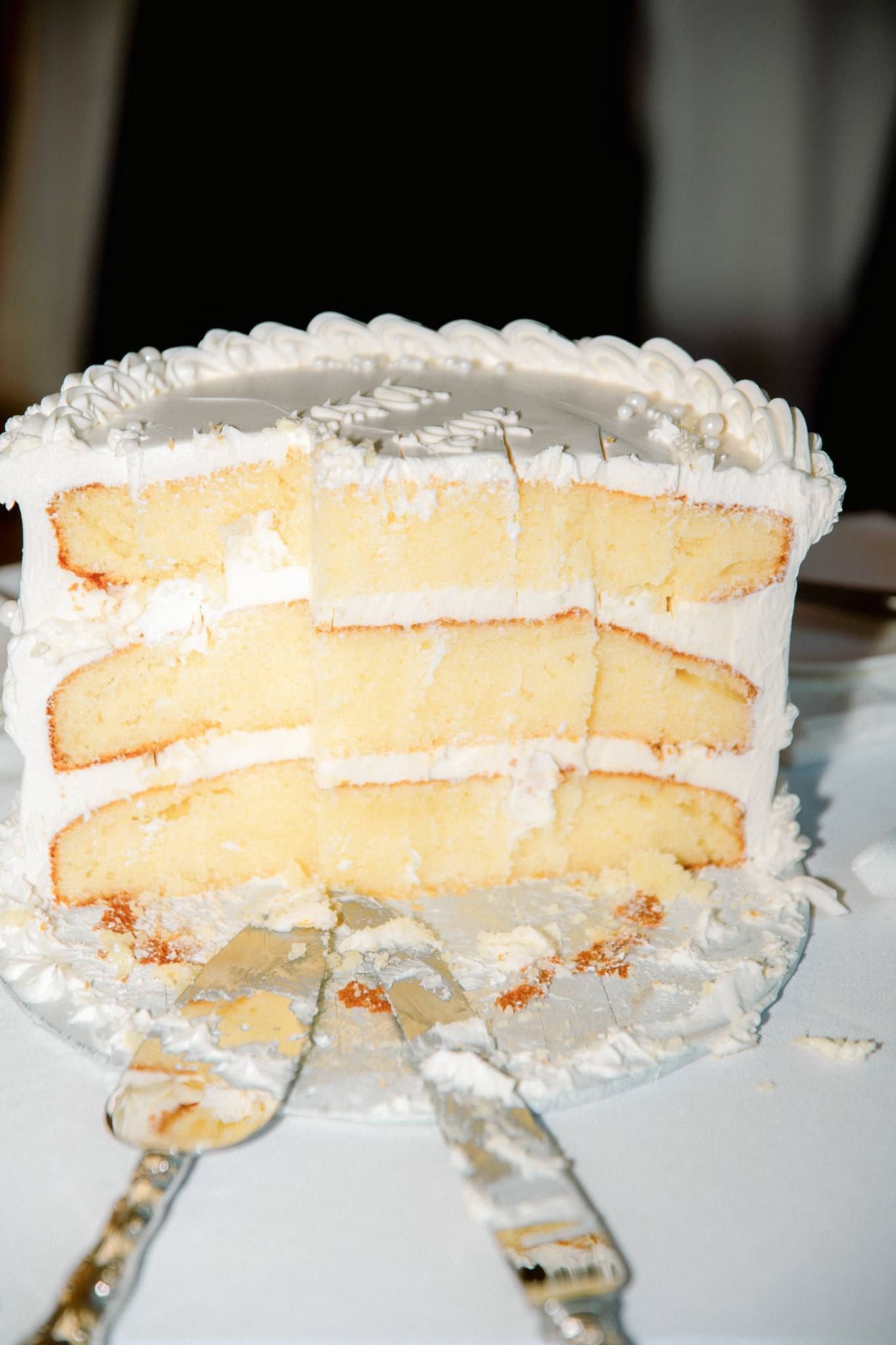 Slice cut from the white wedding cake on a plate