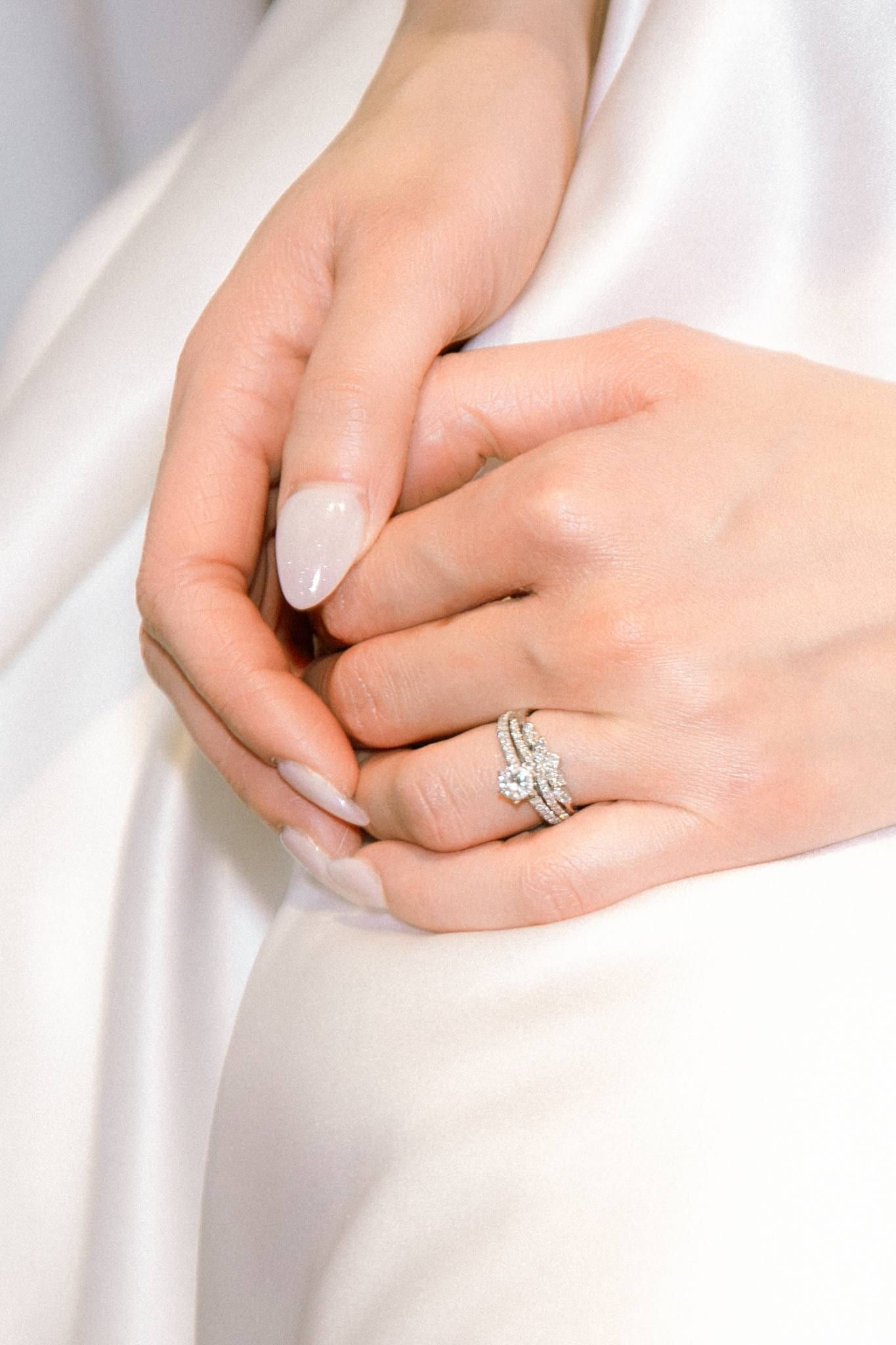 Close-up of the bride's ring hand resting on her gown