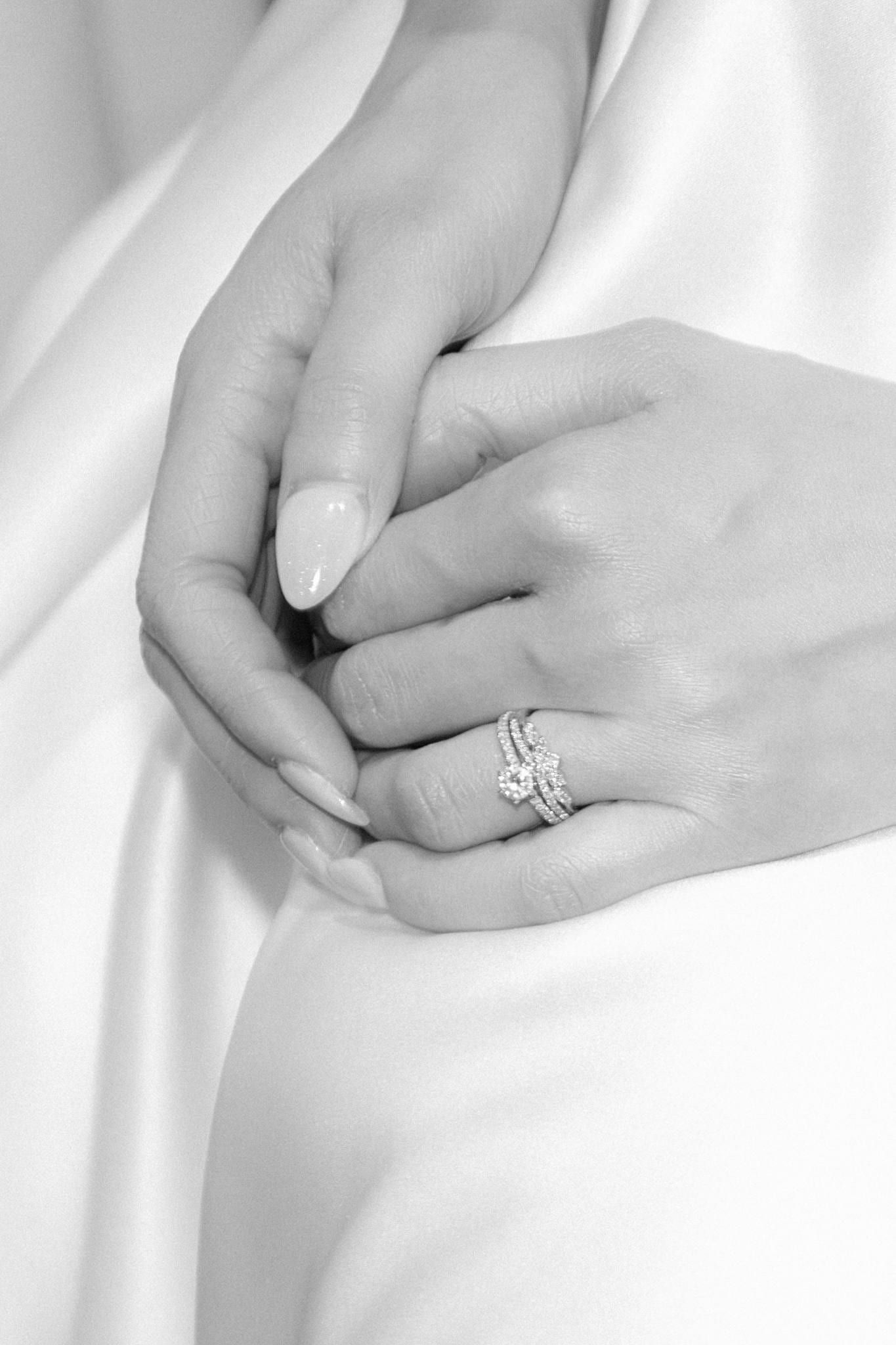 Black-and-white close-up of the bride's ring hand on her gown