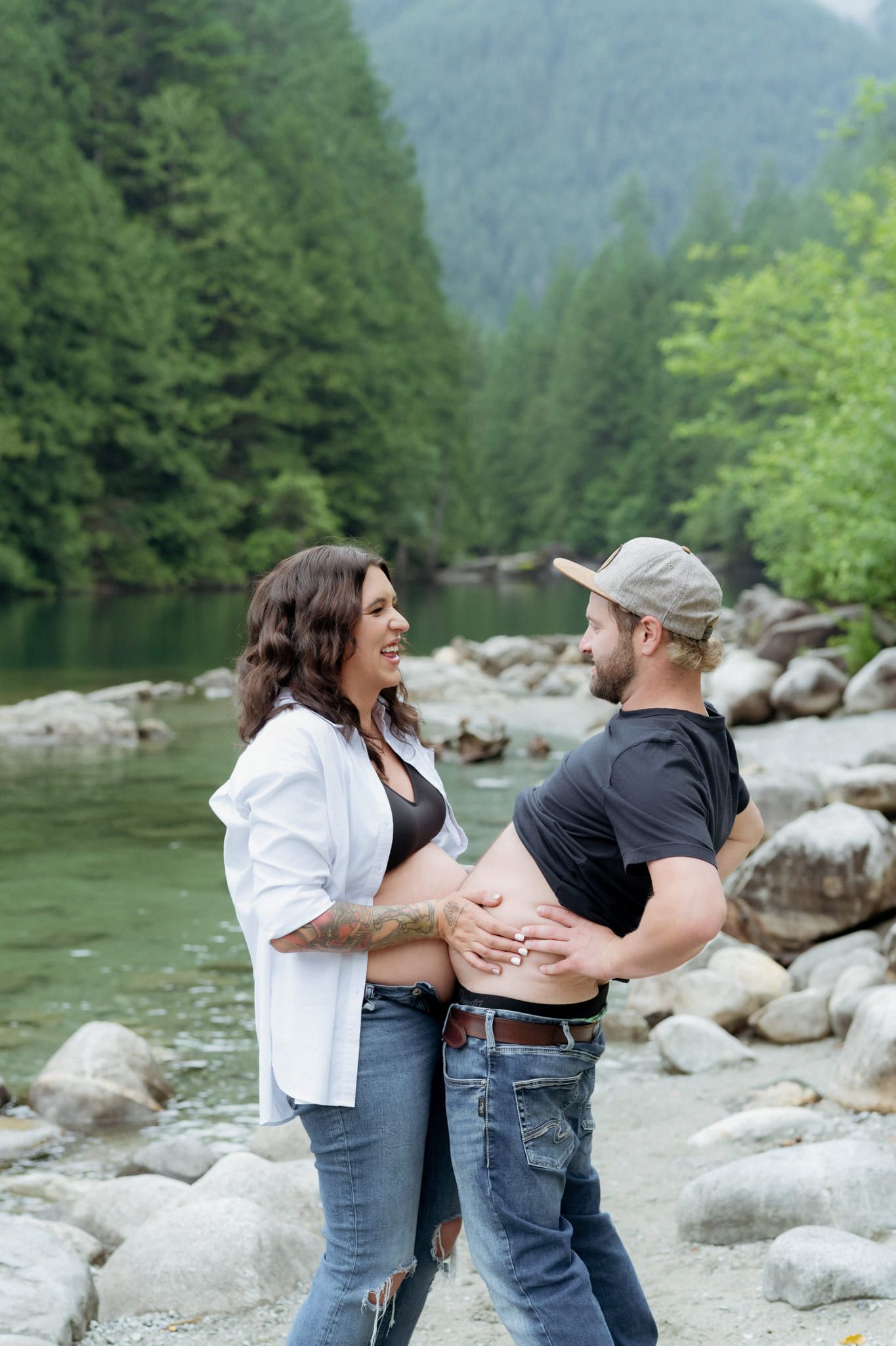 Professional maternity photography, expecting couple on the riverbank in a forested canyon