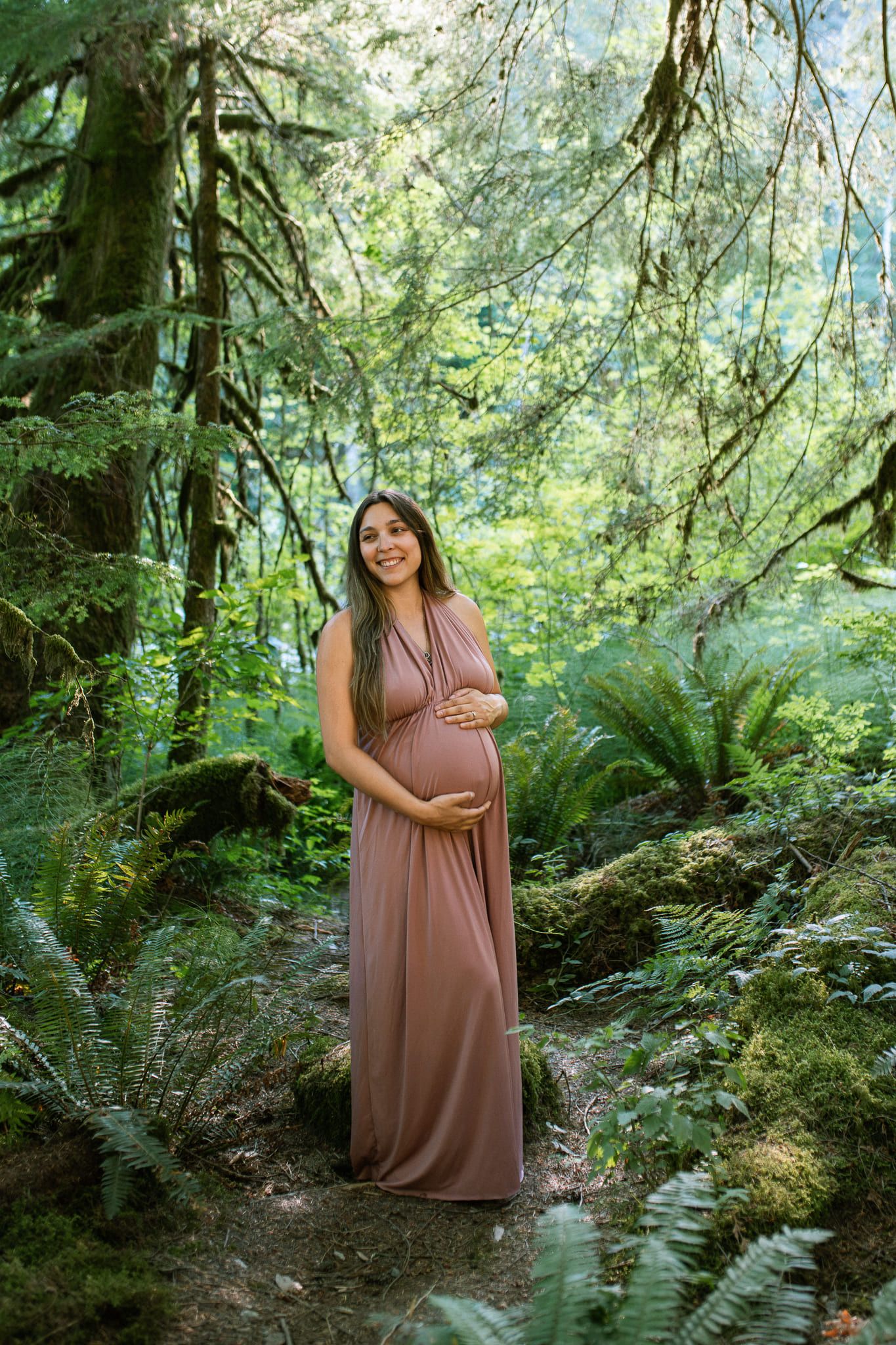 Maternity photos in Coquitlam, expectant mother in a rose gown among ferns in the forest
