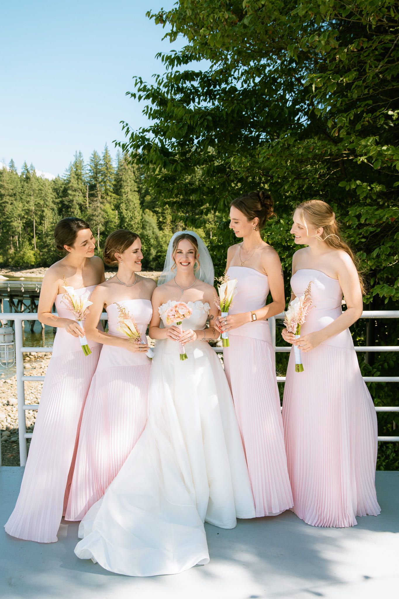 Bride photoshoot on a deck by the forest, bride with her bridesmaids in pink
