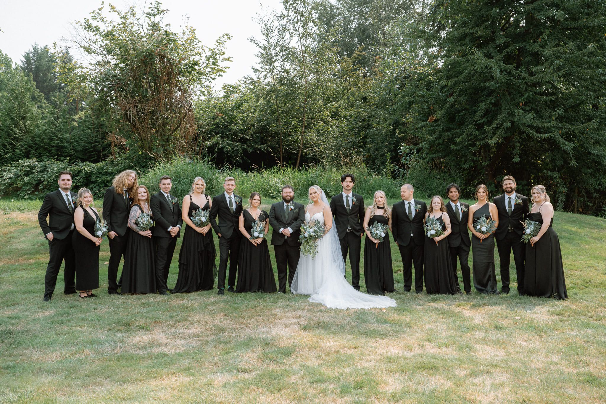 Wedding outdoor shoot on a forest lawn, whole wedding party standing in a line