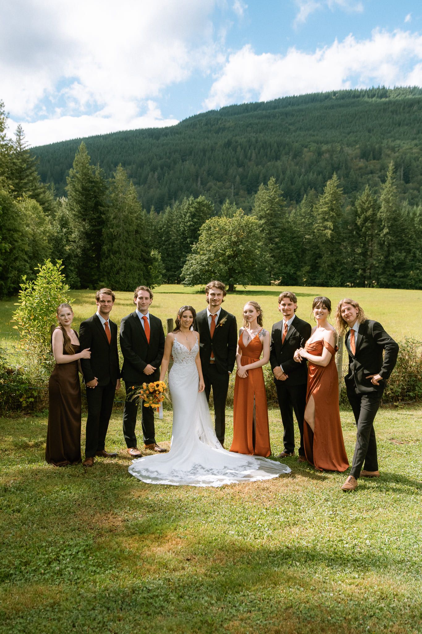 Classic wedding photos, wedding party standing on a lawn below forested hills