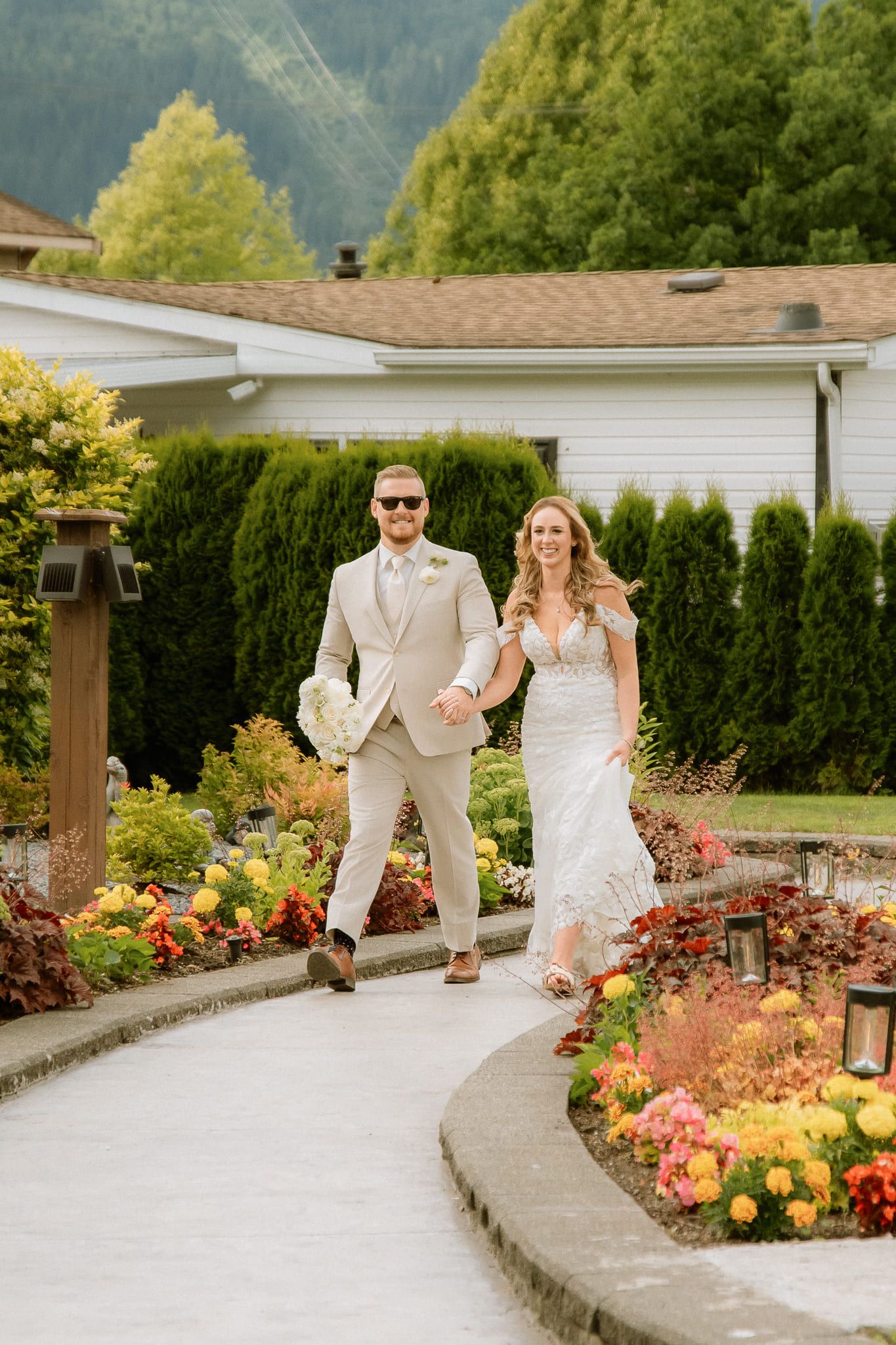 Bride and groom walking along a garden path past bright flowers, by Langley wedding photographer Natalie Varro
