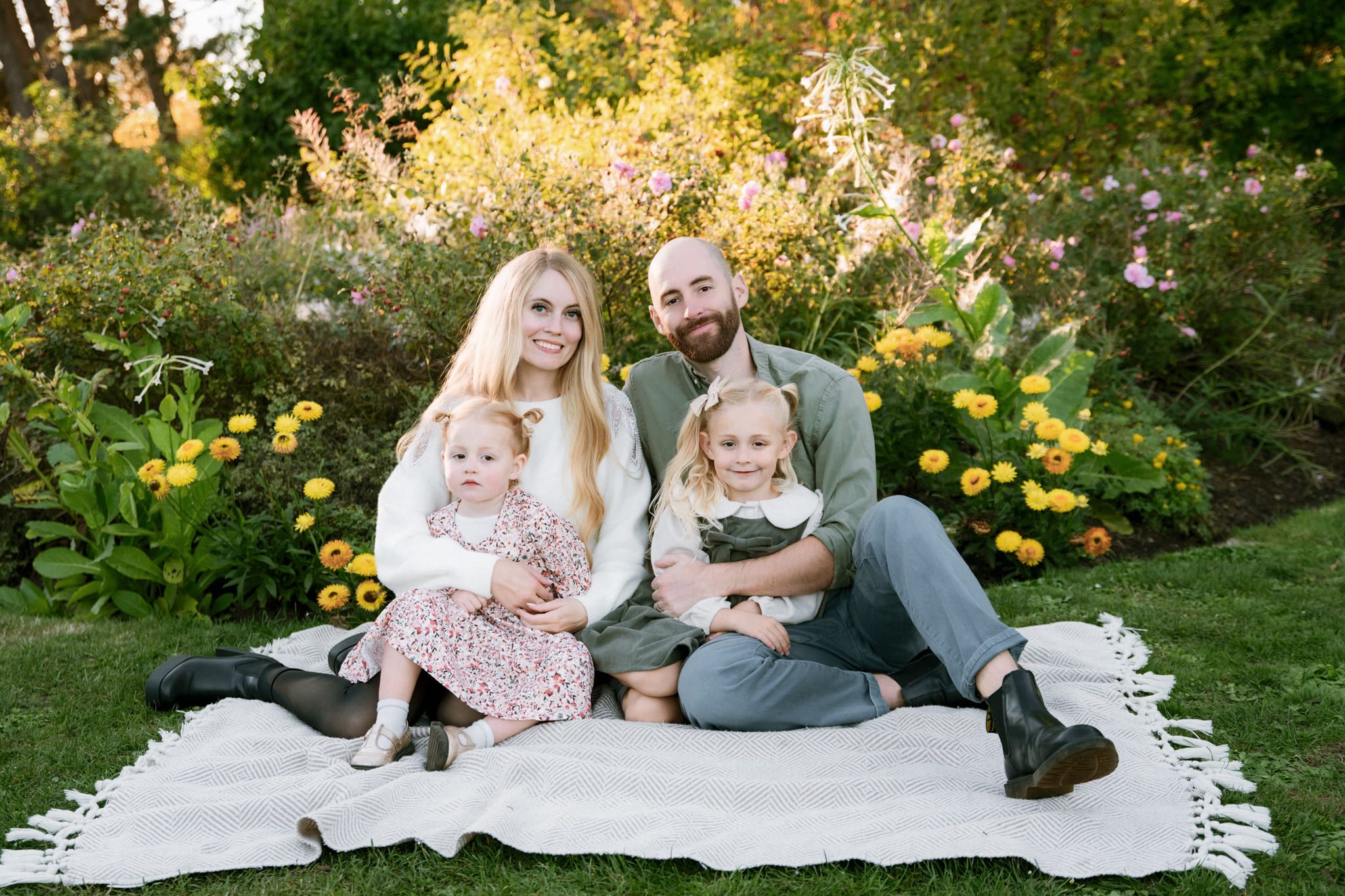 Family pictures in a flower garden, parents and two little girls on a blanket