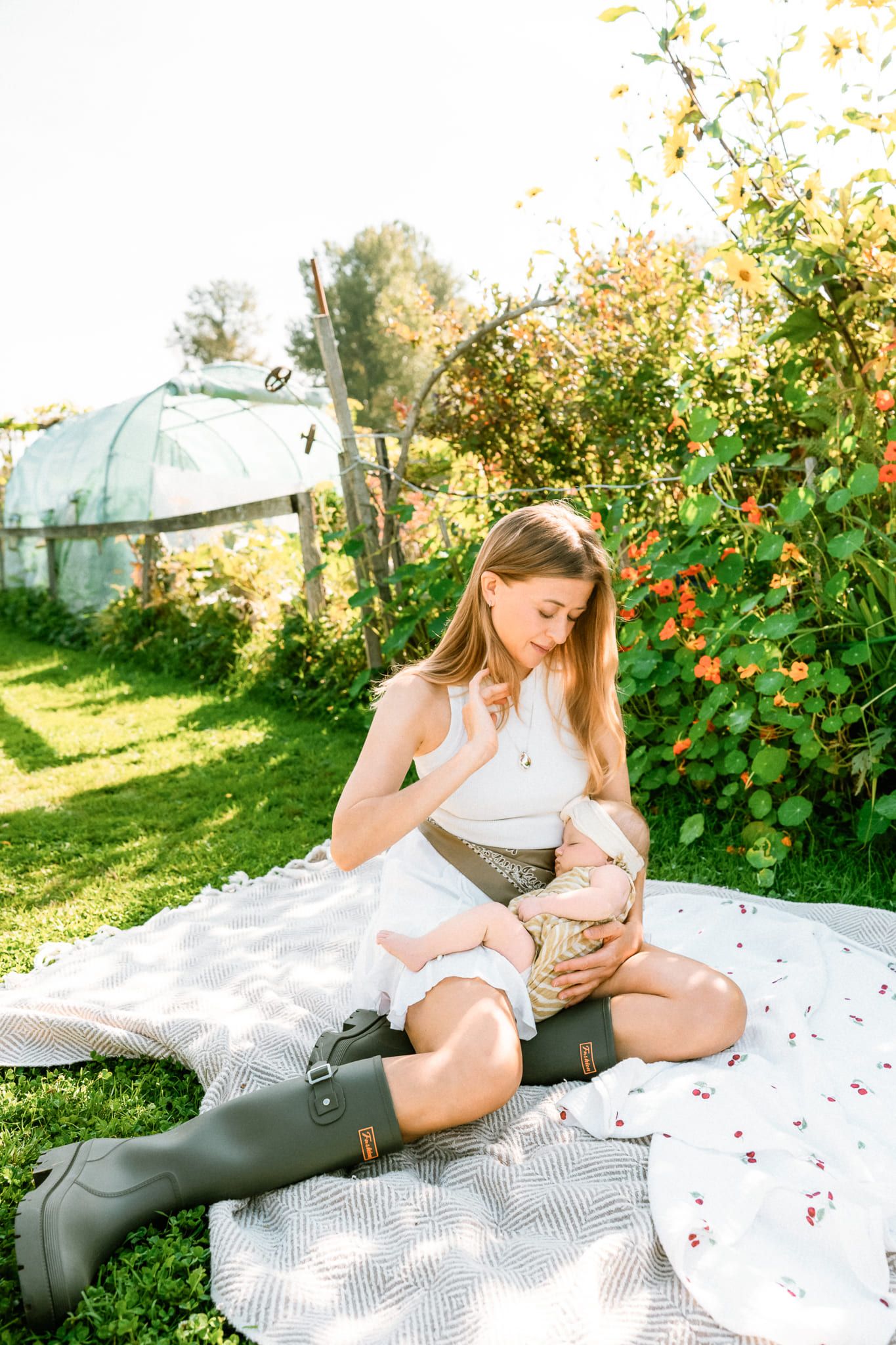 Newborn outdoor photos in a sunny flower garden, mother holding her baby