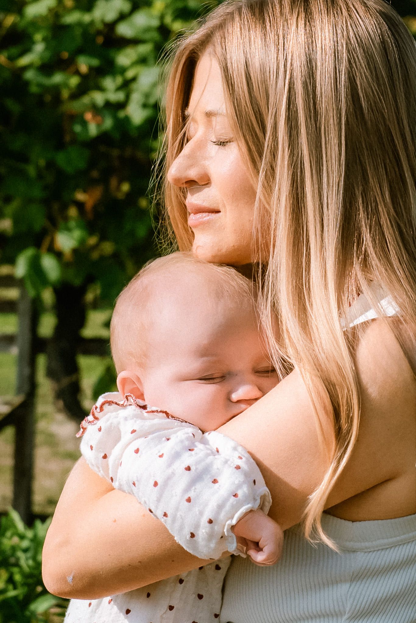 Port Moody newborn photos, mother holding her baby in a sunny flower garden