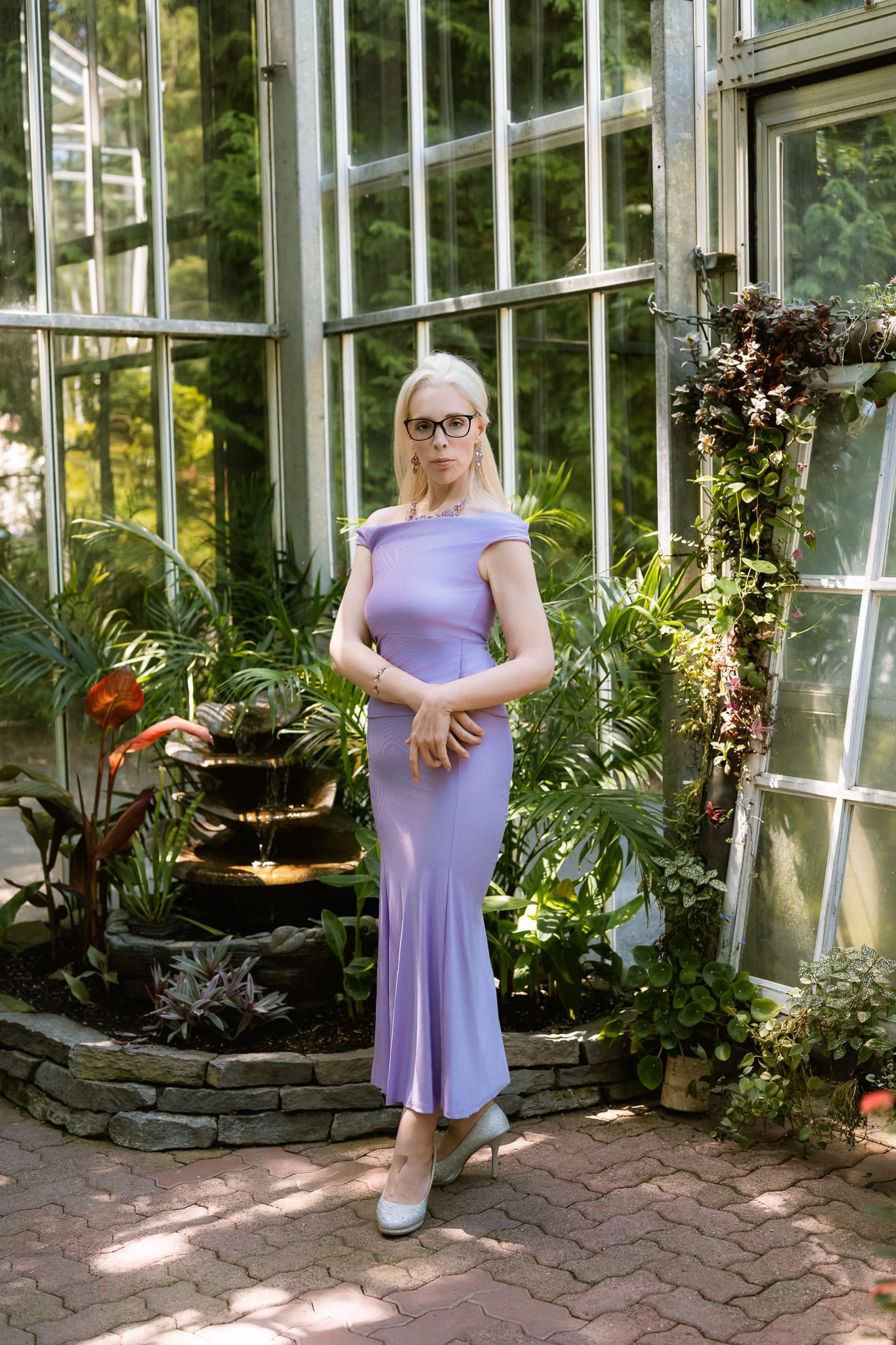 Portrait photo in a greenhouse garden, woman in a lilac dress and glasses