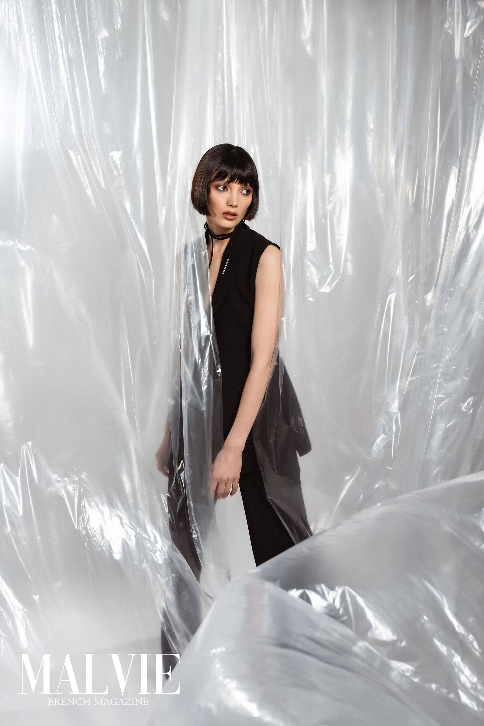 Model with a dark bob in black against crinkled plastic, from a Malvie feature