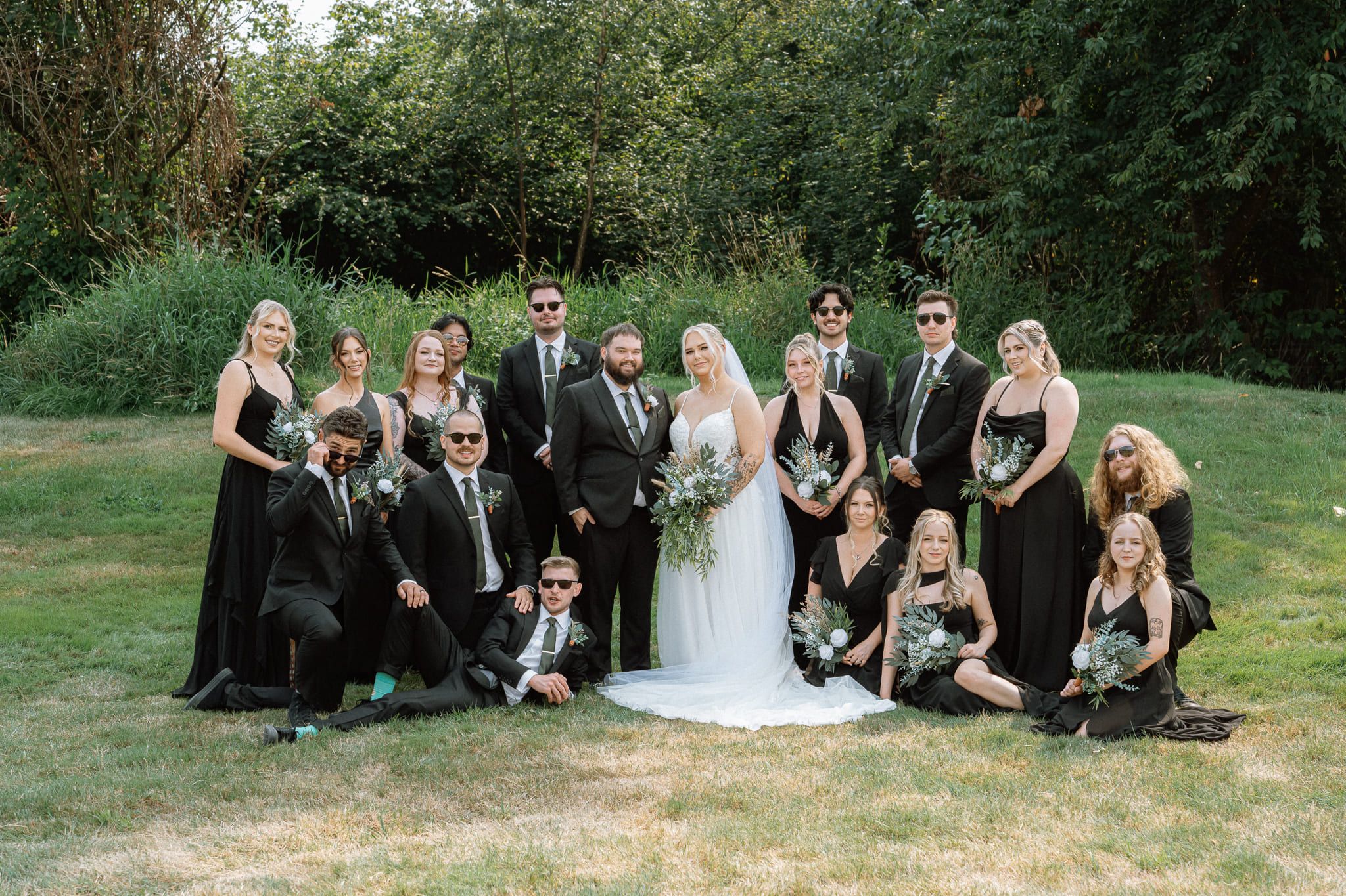 Wedding outdoor photoshoot, large wedding party sitting and standing on a lawn
