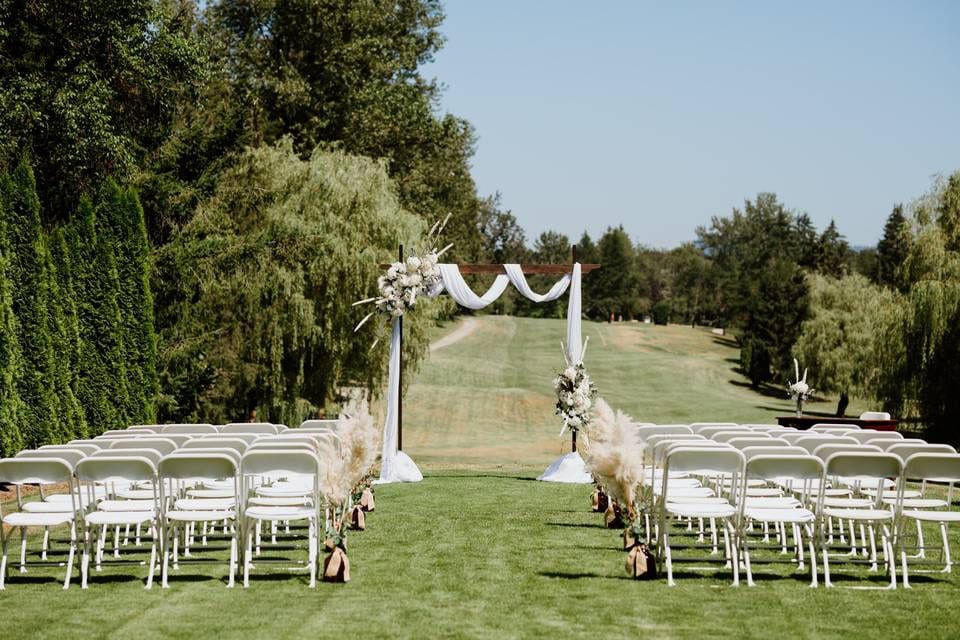 Wedding outdoor photoshoot, ceremony chairs facing a flower arch on the lawn at Fort Langley Golf Course
