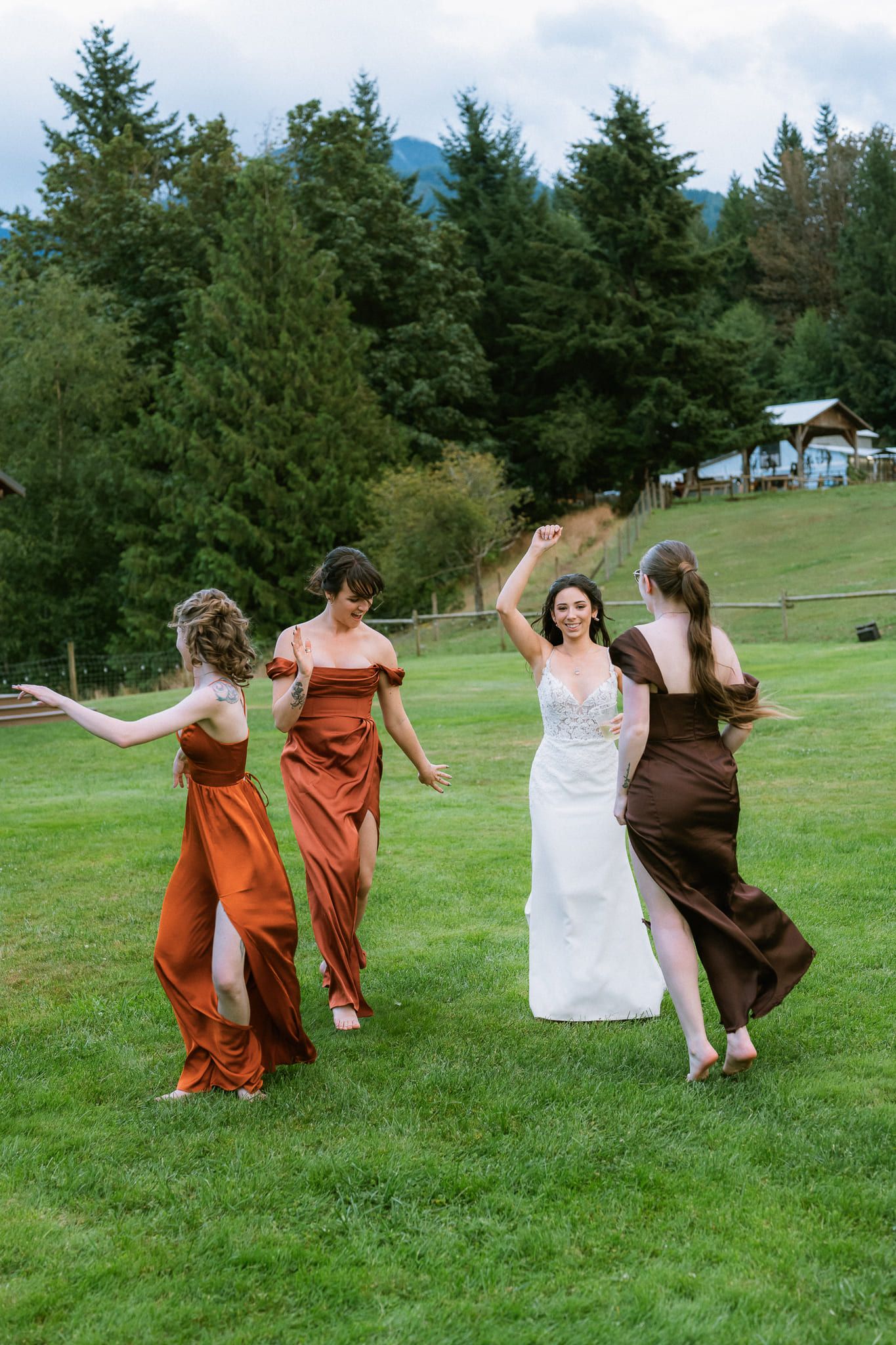 Fun wedding photos, bride dancing on the lawn with her bridesmaids in rust dresses
