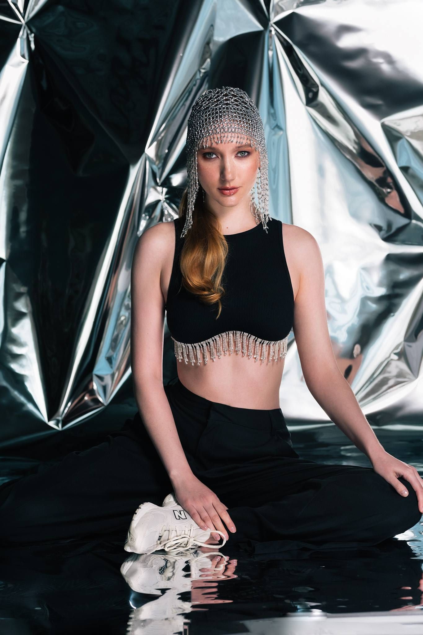 Model in a chainmail headpiece seated against a foil backdrop