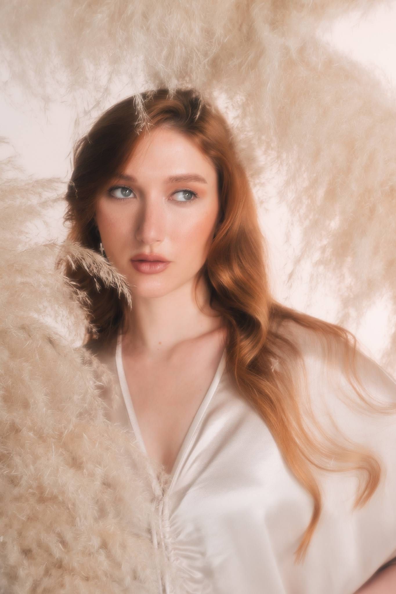 Red-haired model in a cream satin blouse among dried pampas grass
