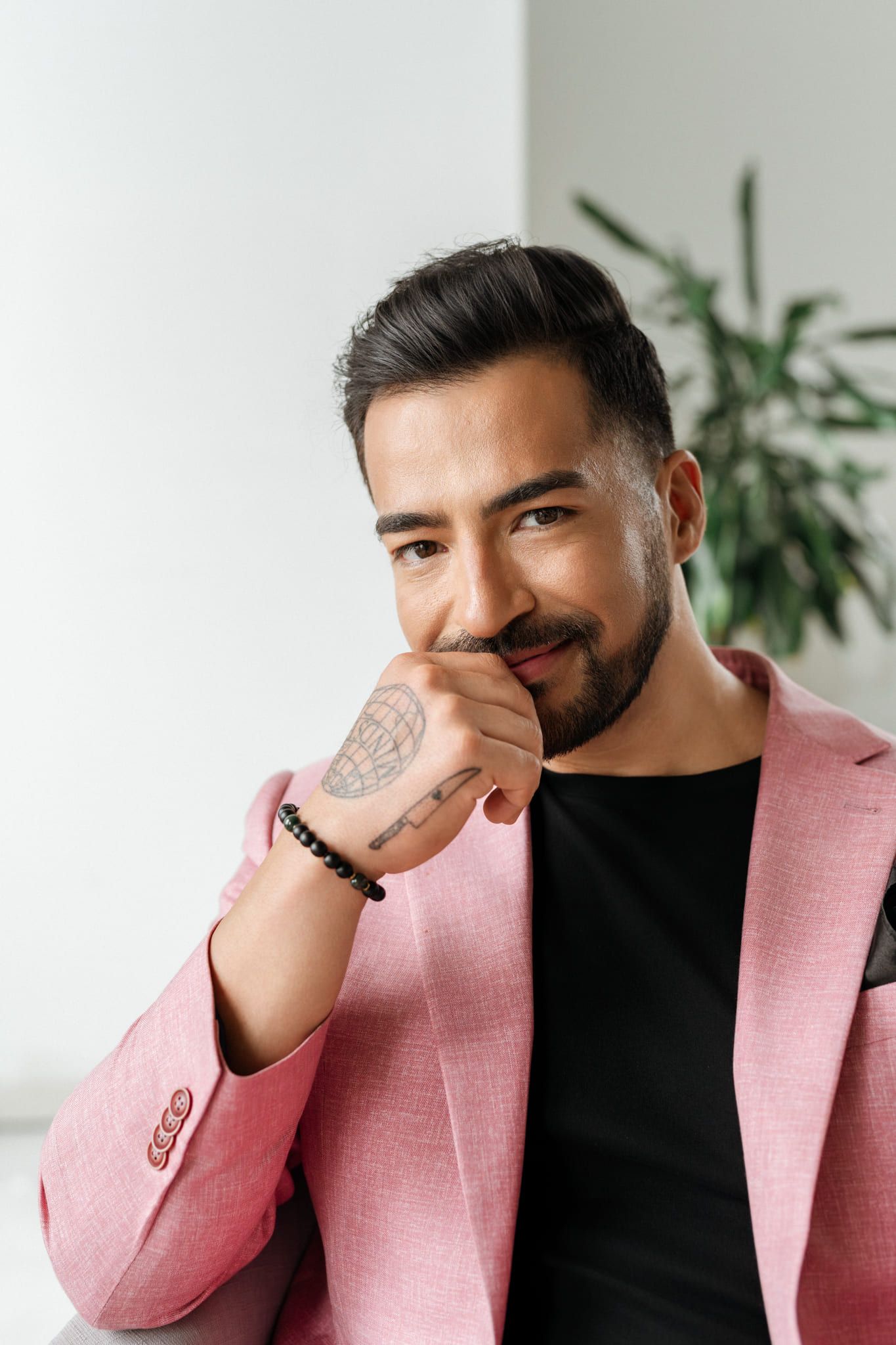 Business portrait photo, man in a pink blazer smiling with his hand to his chin