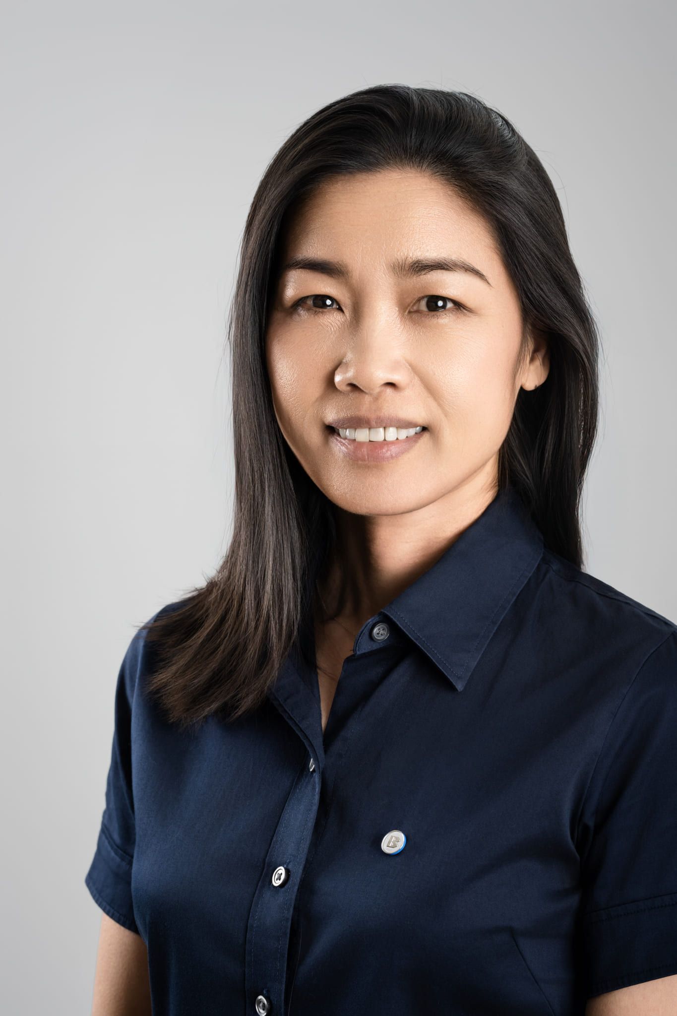 Corporate business photography, professional headshot of a smiling woman in a navy shirt