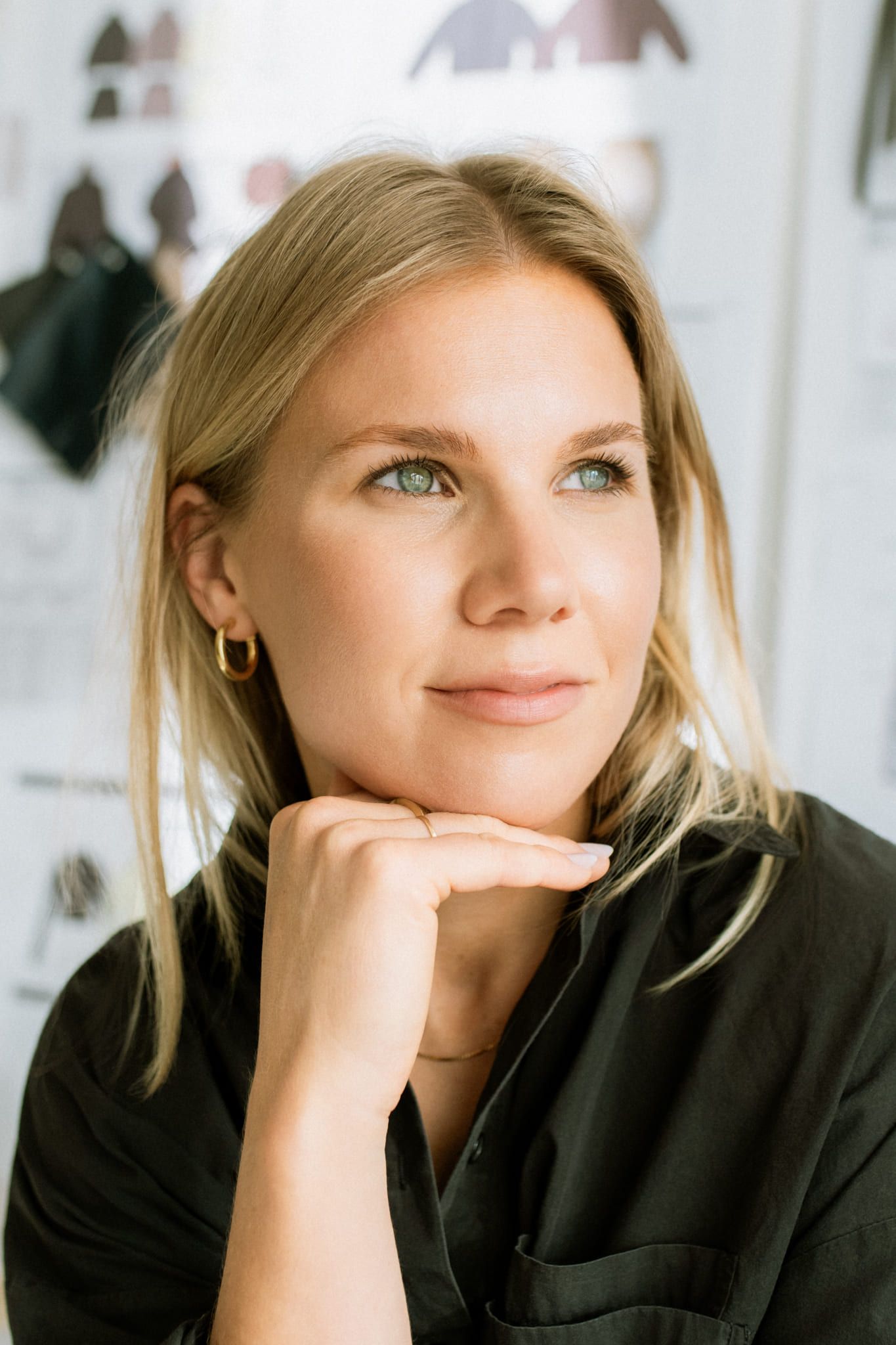 Professional corporate photo, blonde woman in a dark jacket resting her chin on her hand