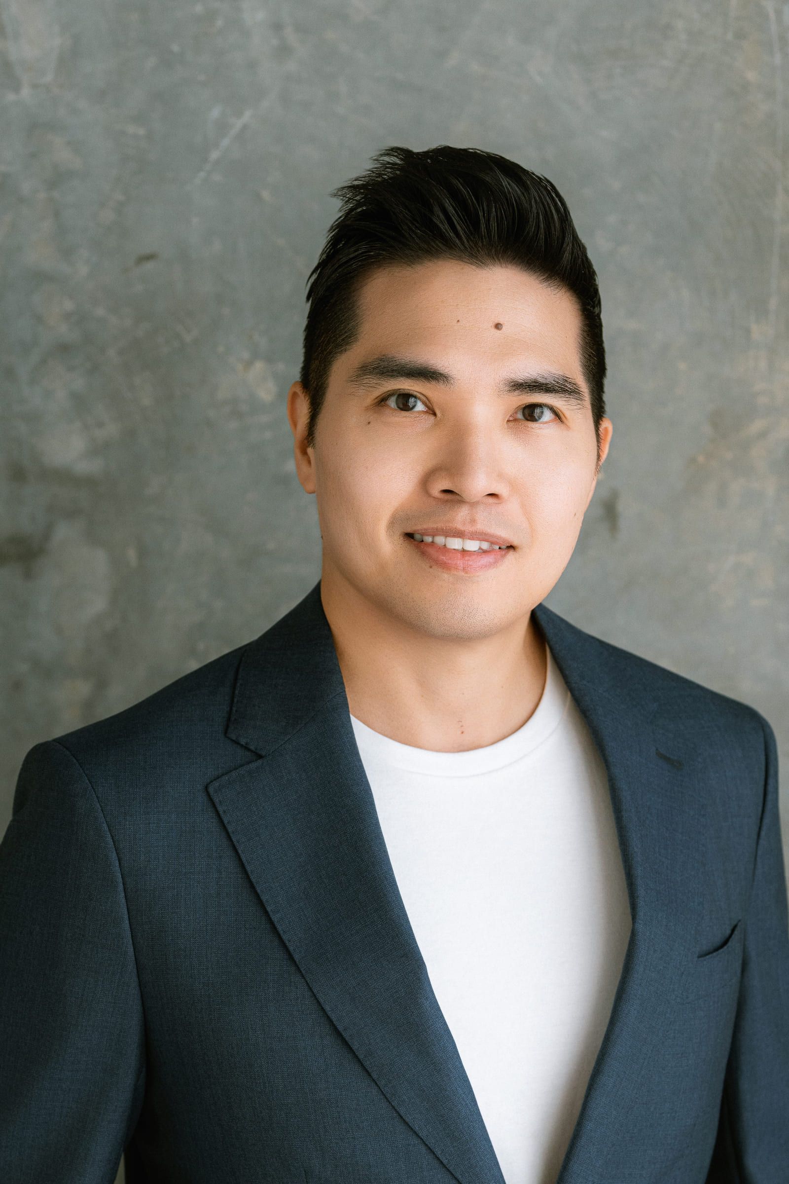 Corporate business photography, professional headshot of a smiling man in a navy blazer