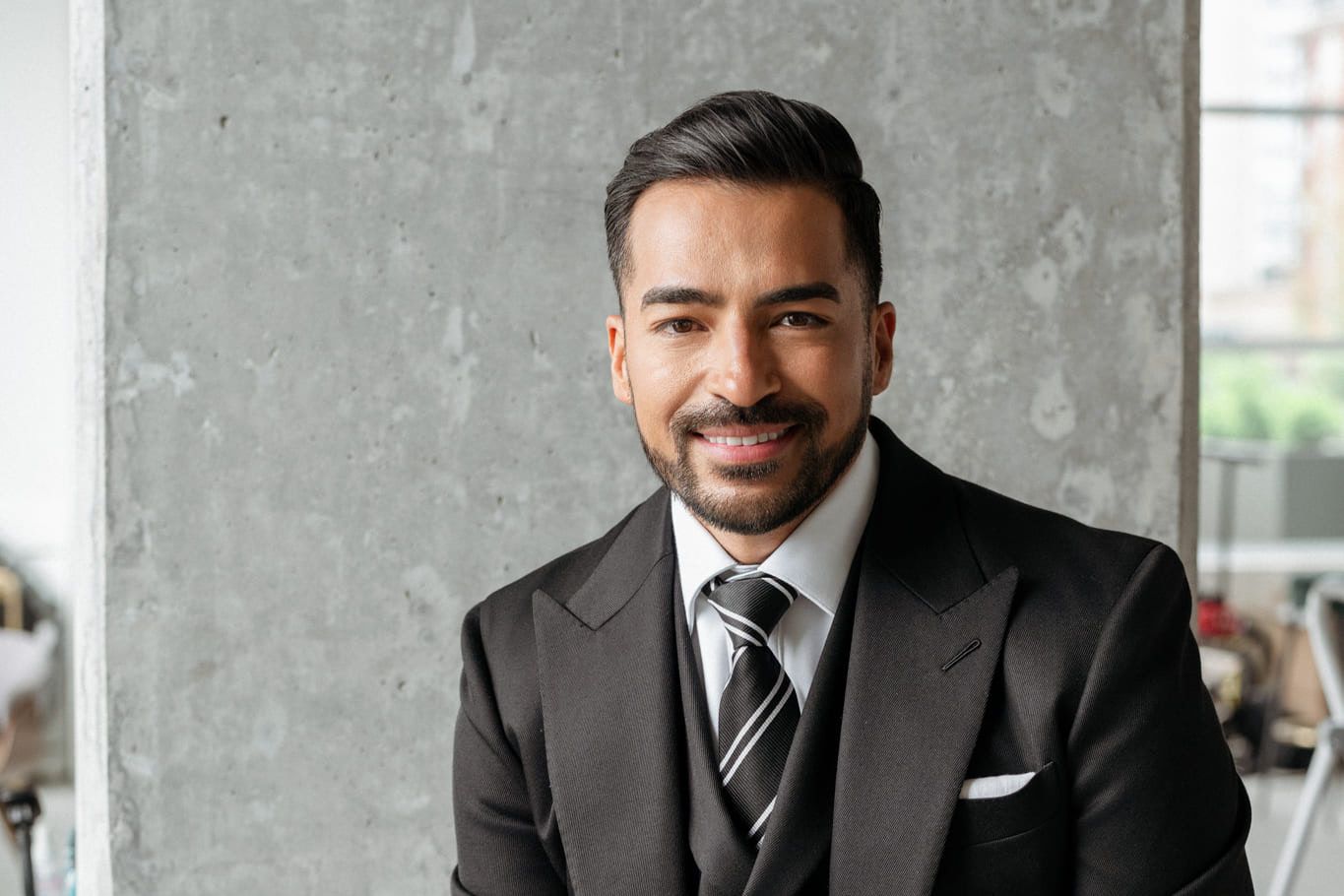 Small business branding photography, smiling man in a dark suit and striped tie by a concrete wall