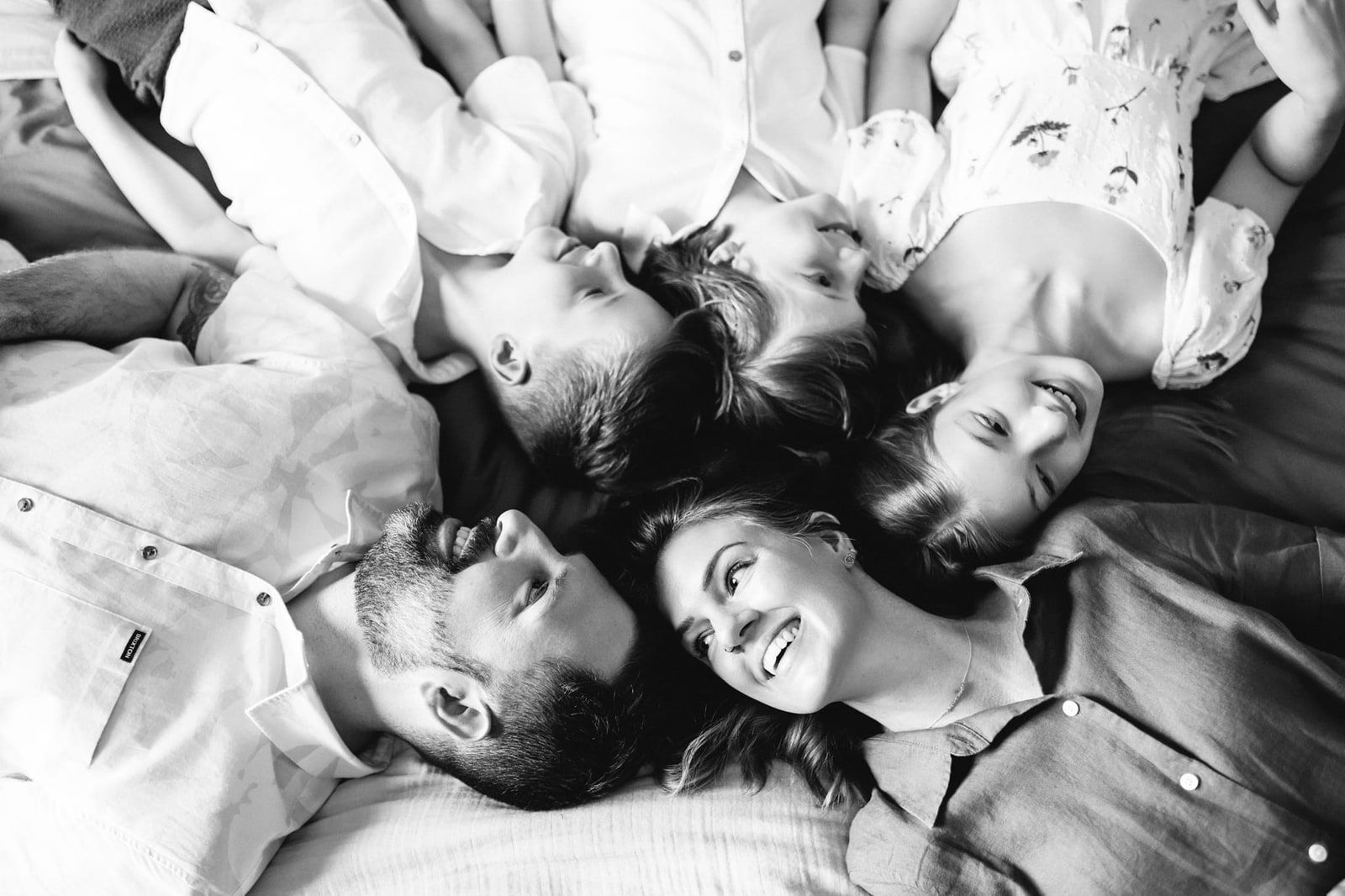 Family home photoshoot, family of five lying head to head on a bed, in black and white
