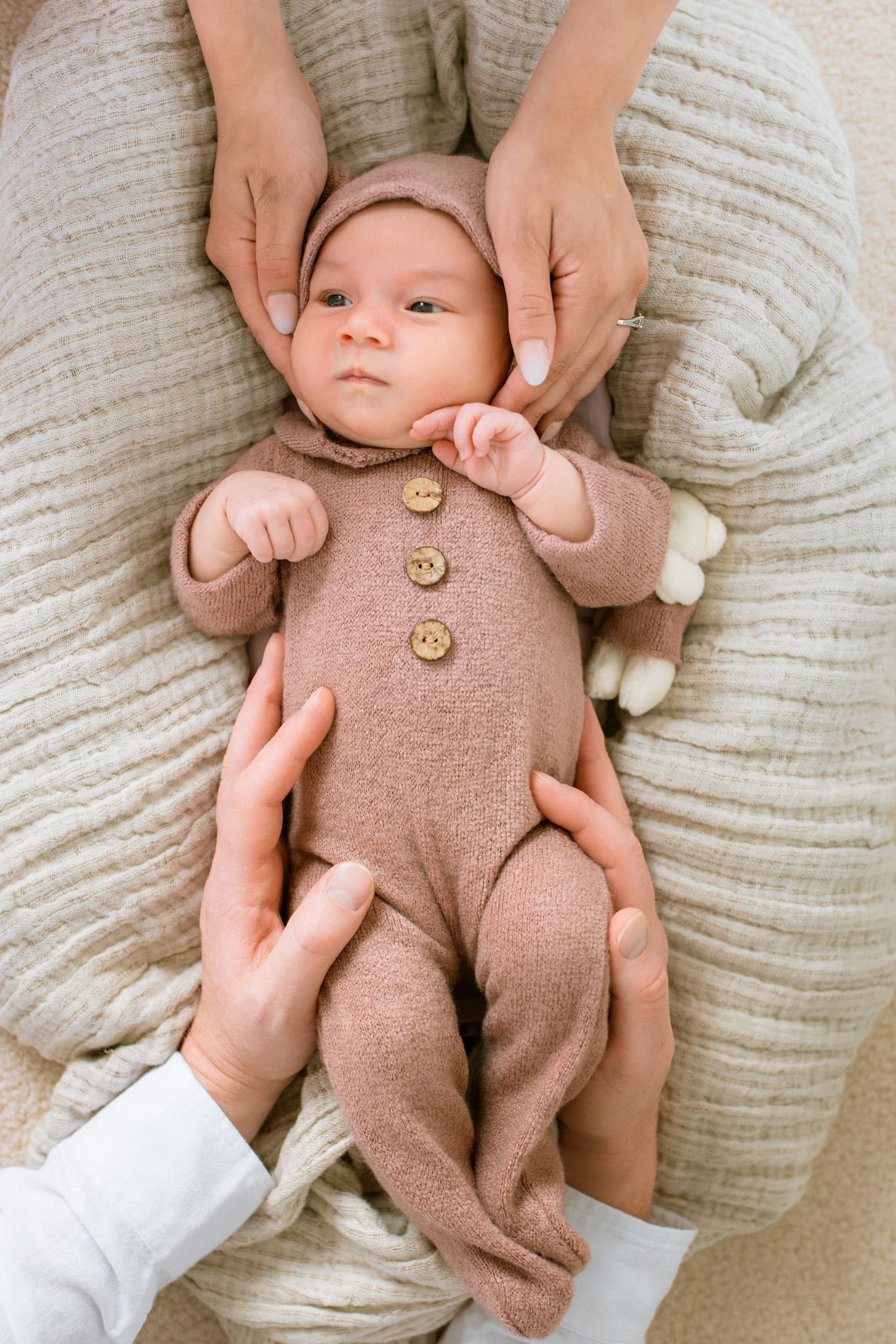 Newborn shoot at home, newborn in a pink knit romper and bear hood