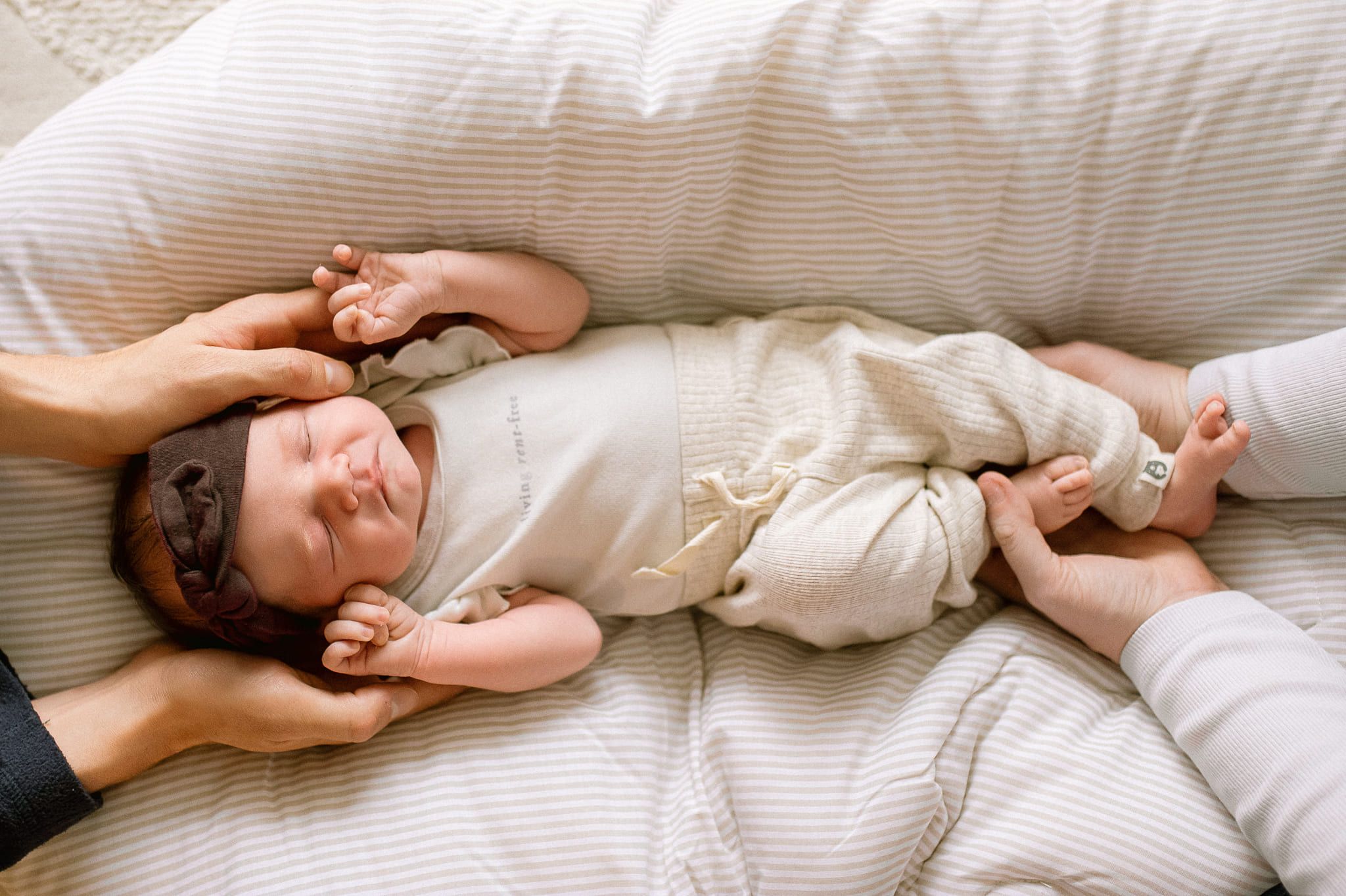 Newborn photography in Coquitlam, newborn baby girl in cream, cuddled by her parents at home
