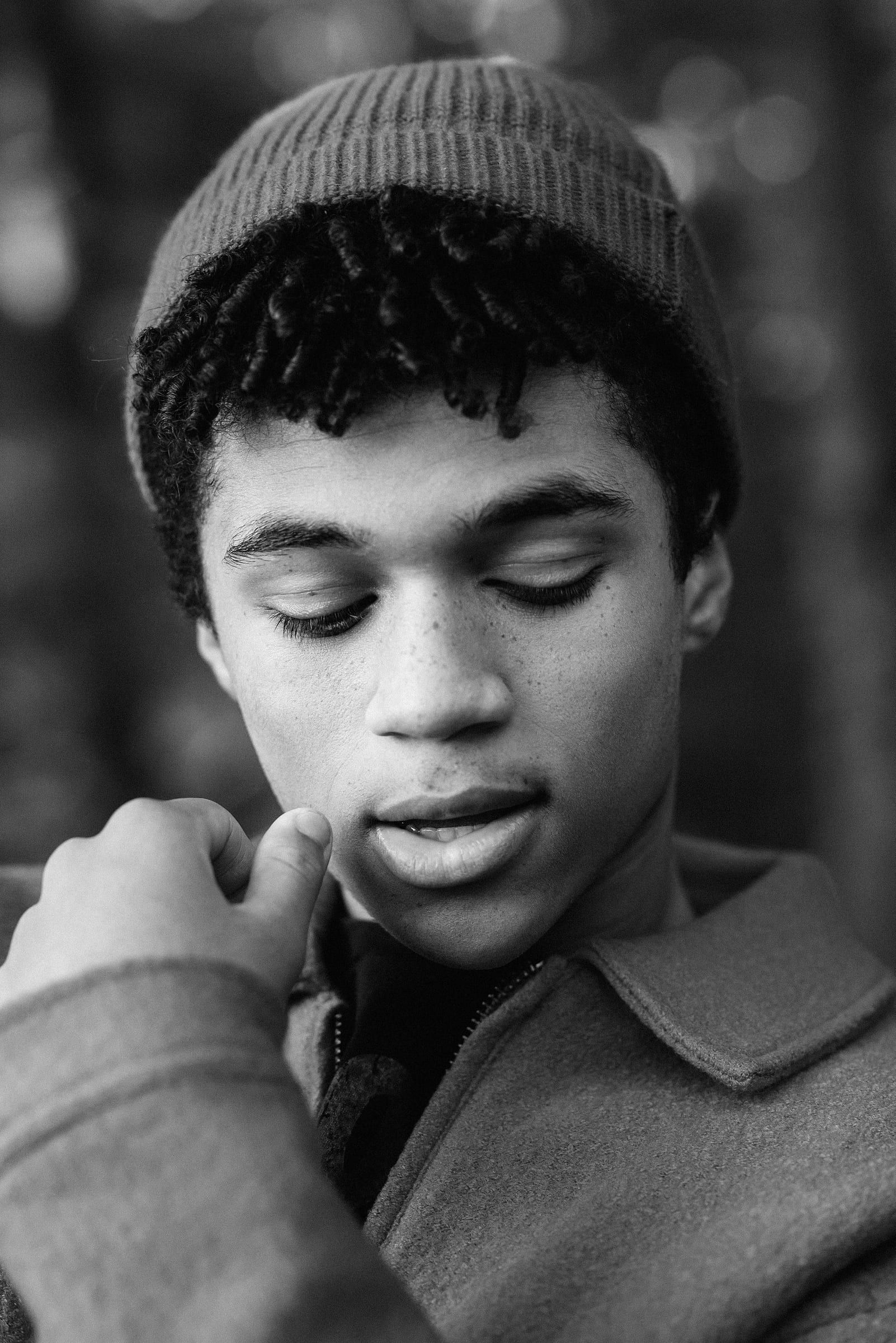 Black-and-white portrait of a young man in a dark coat with his eyes closed