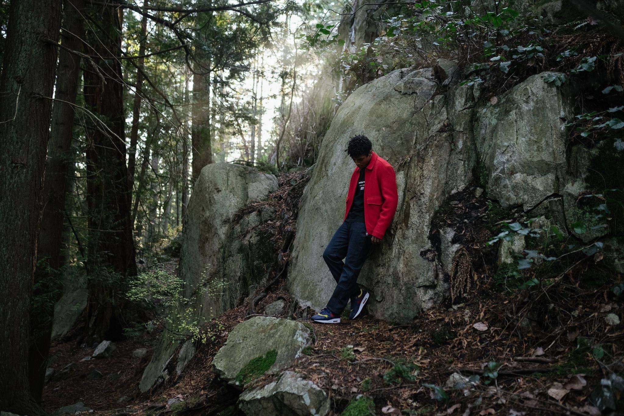 Person in a red jacket walking on a mossy rock in a forest