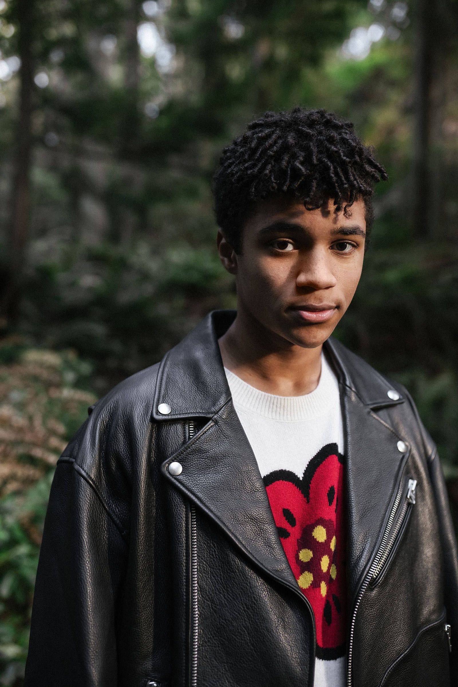 Young man in a leather jacket and printed tee among trees