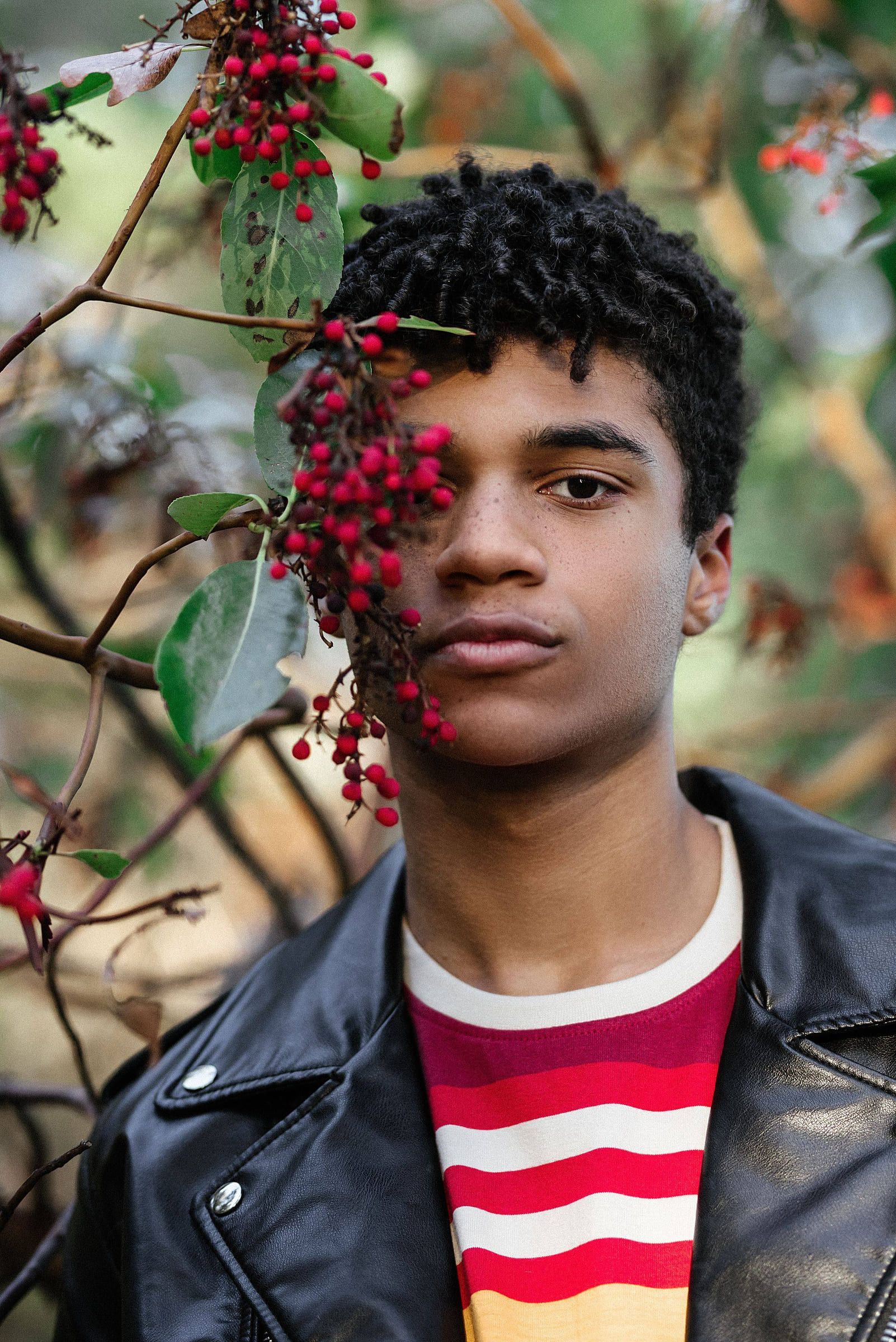 Young man in a leather jacket among red berries