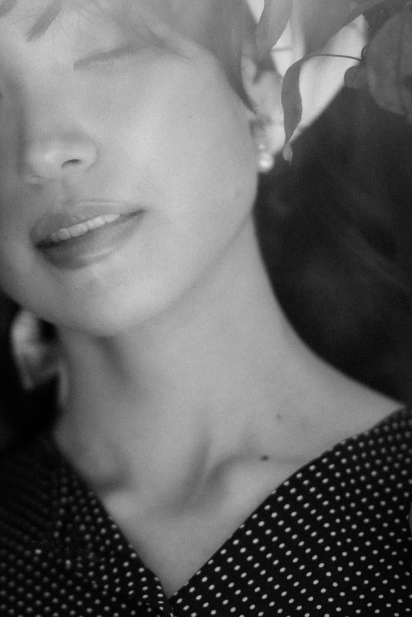 Black-and-white close-up of a model with eyes closed in a polka-dot top
