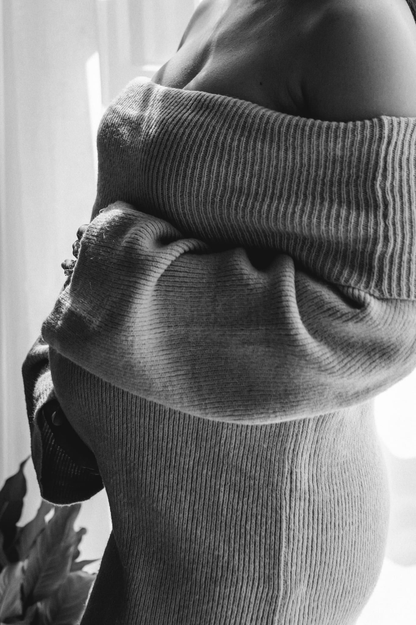 Professional pregnancy photography, close-up of hands on a baby bump in a knit sweater, in black and white