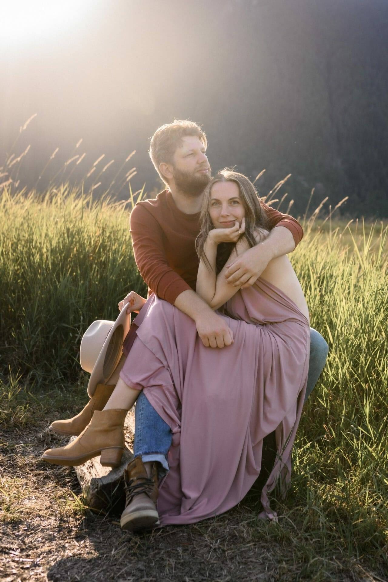 Field engagement photos in tall golden grass, couple sitting together