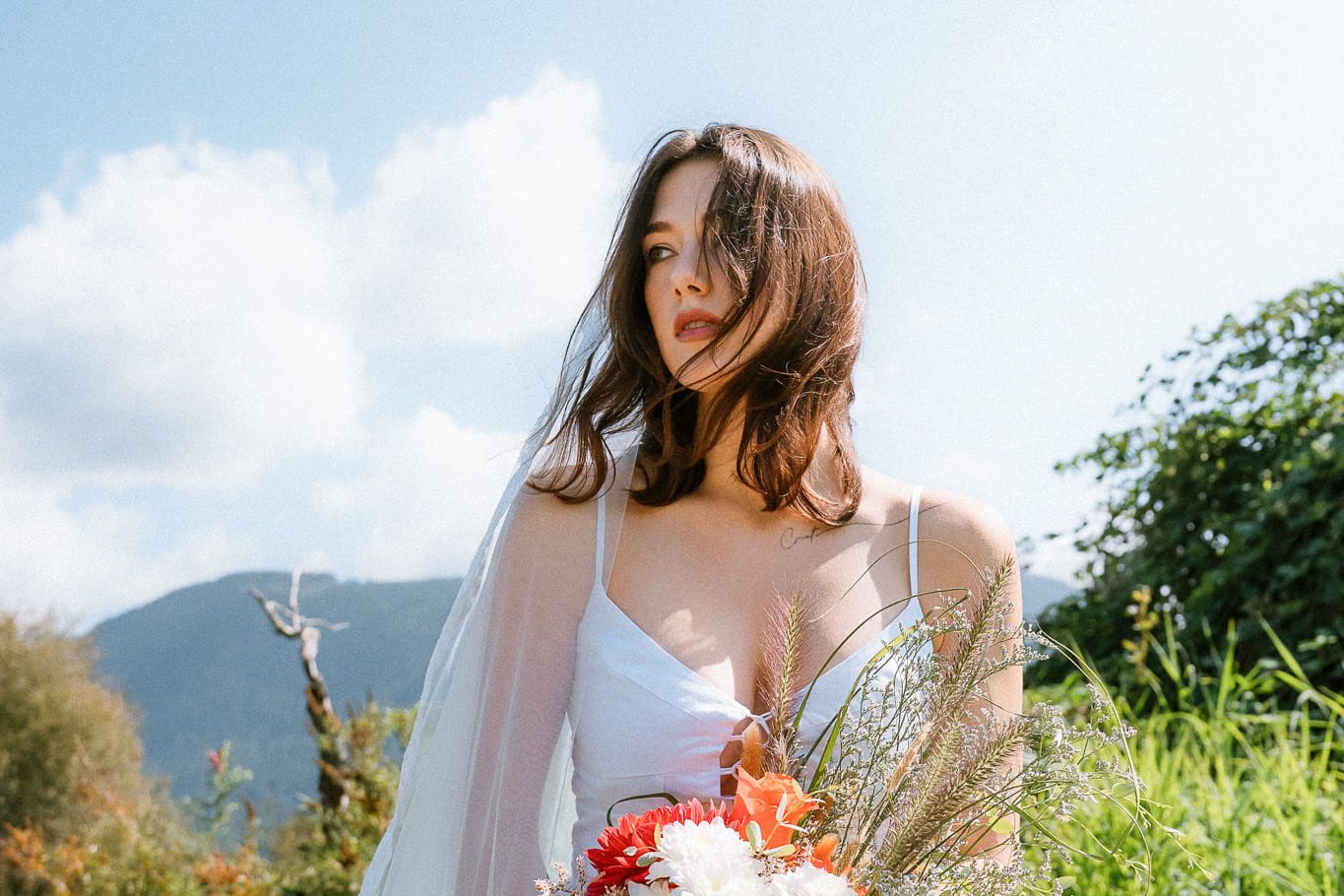 Branding photography in a mountain meadow, woman in white with a bouquet