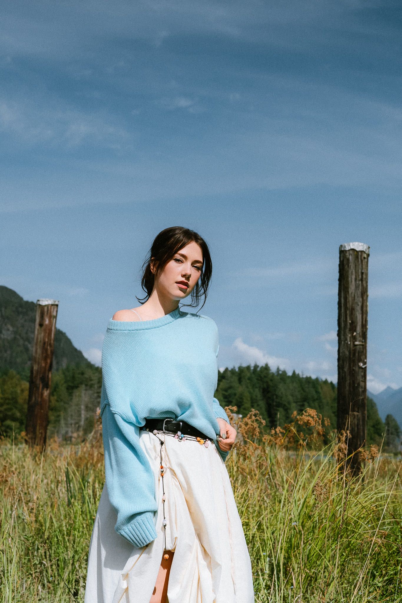 Woman in a blue sweater standing in a meadow under a blue sky, by Langley portrait photographer Natalie Varro