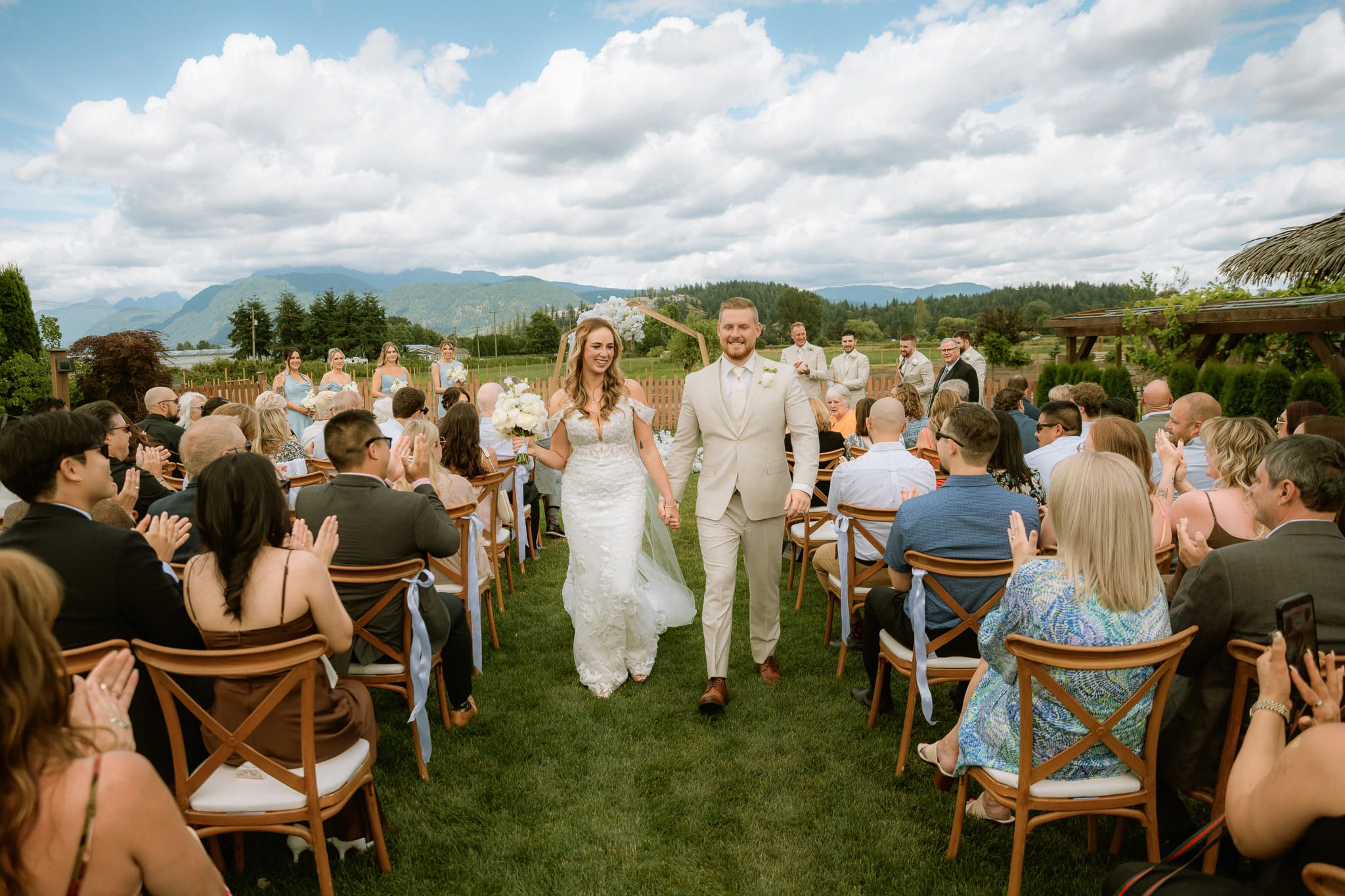 Langley wedding photographer, bride and groom walking up the aisle between guests in a meadow