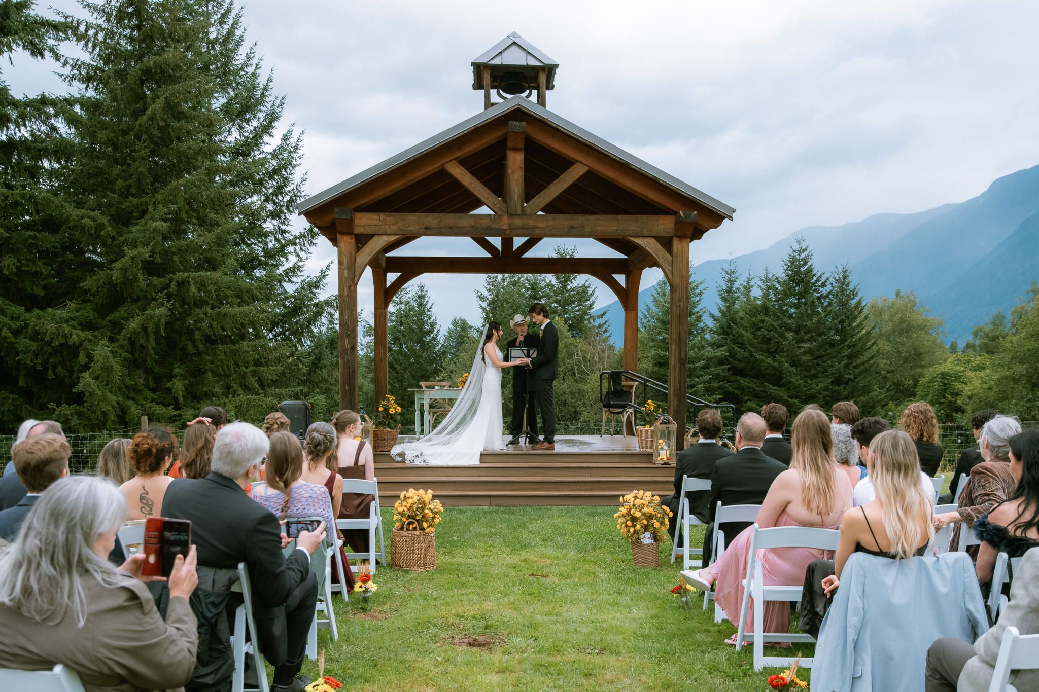 Wedding photography in Coquitlam, wedding ceremony under a wooden gazebo with mountains behind