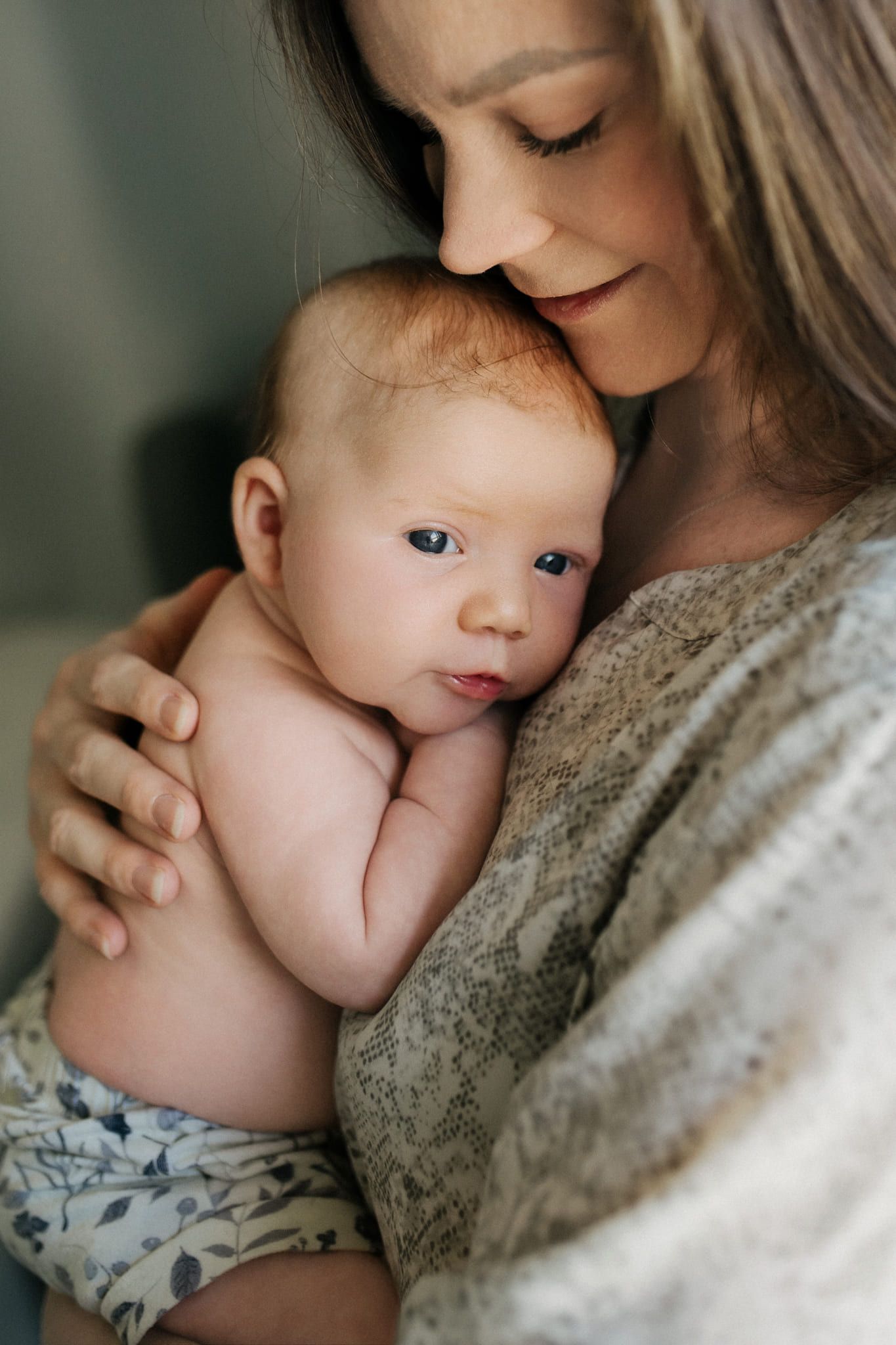 Newborn and mother photography, mother cuddling her baby cheek to cheek