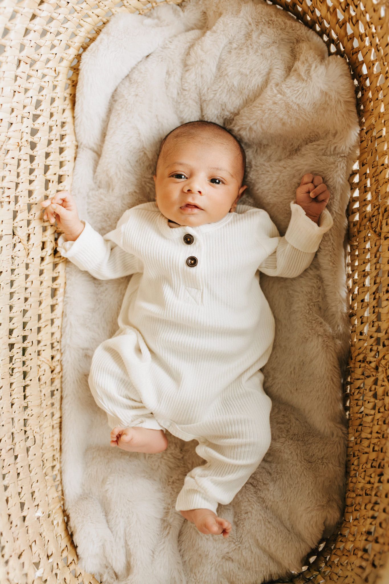 Infant photo, newborn in a white romper lying in a woven basket