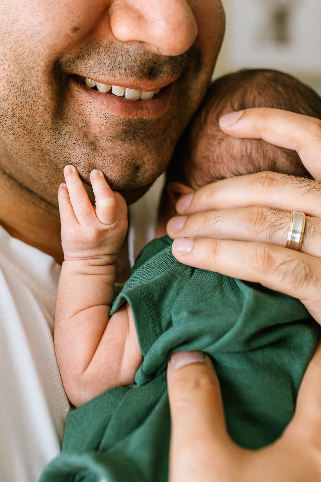 Newborn at home photos, newborn boy in a green bodysuit with his parents in their nursery