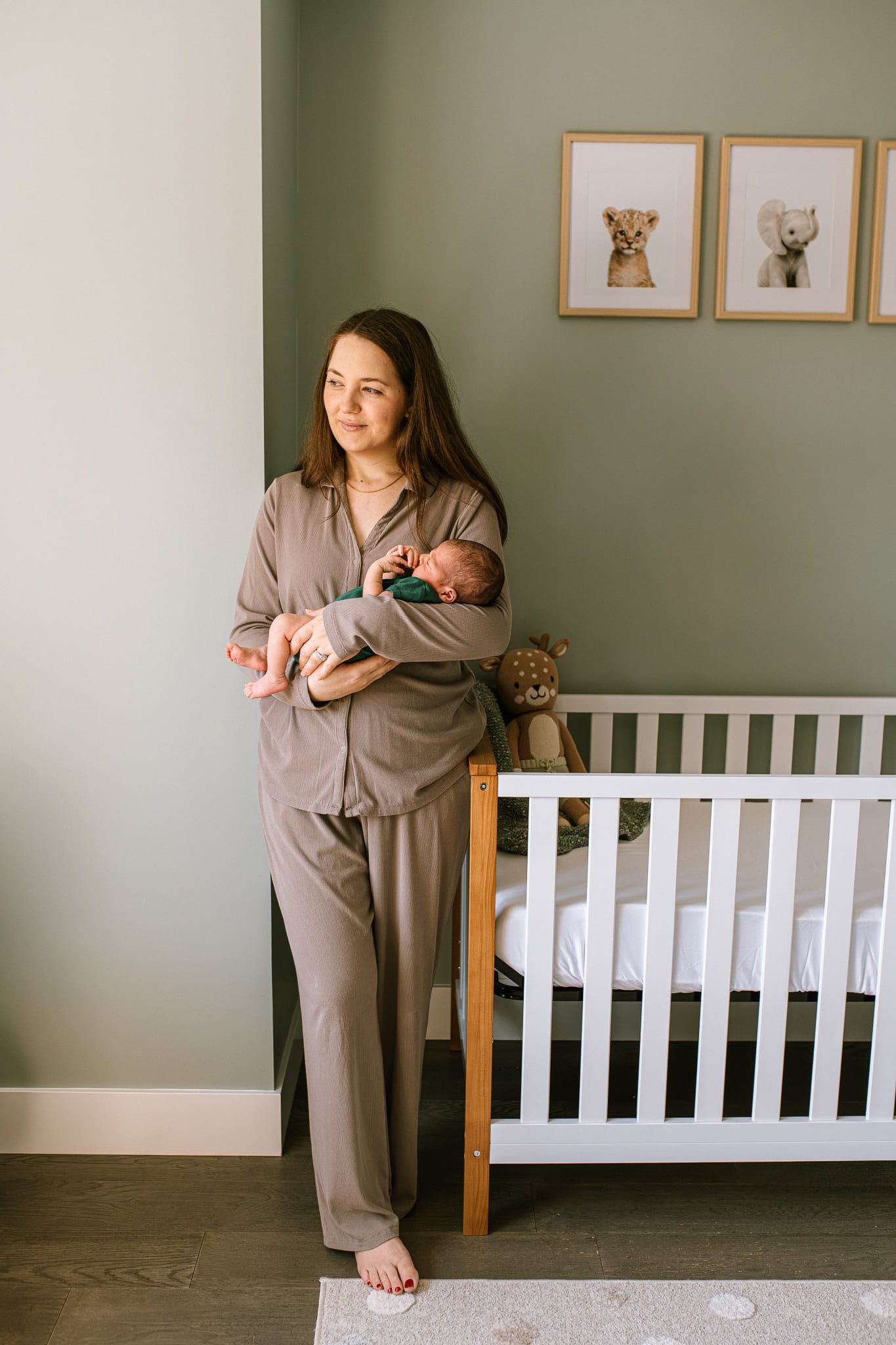 Newborn photos in home, newborn boy in a green bodysuit with his parents in their nursery