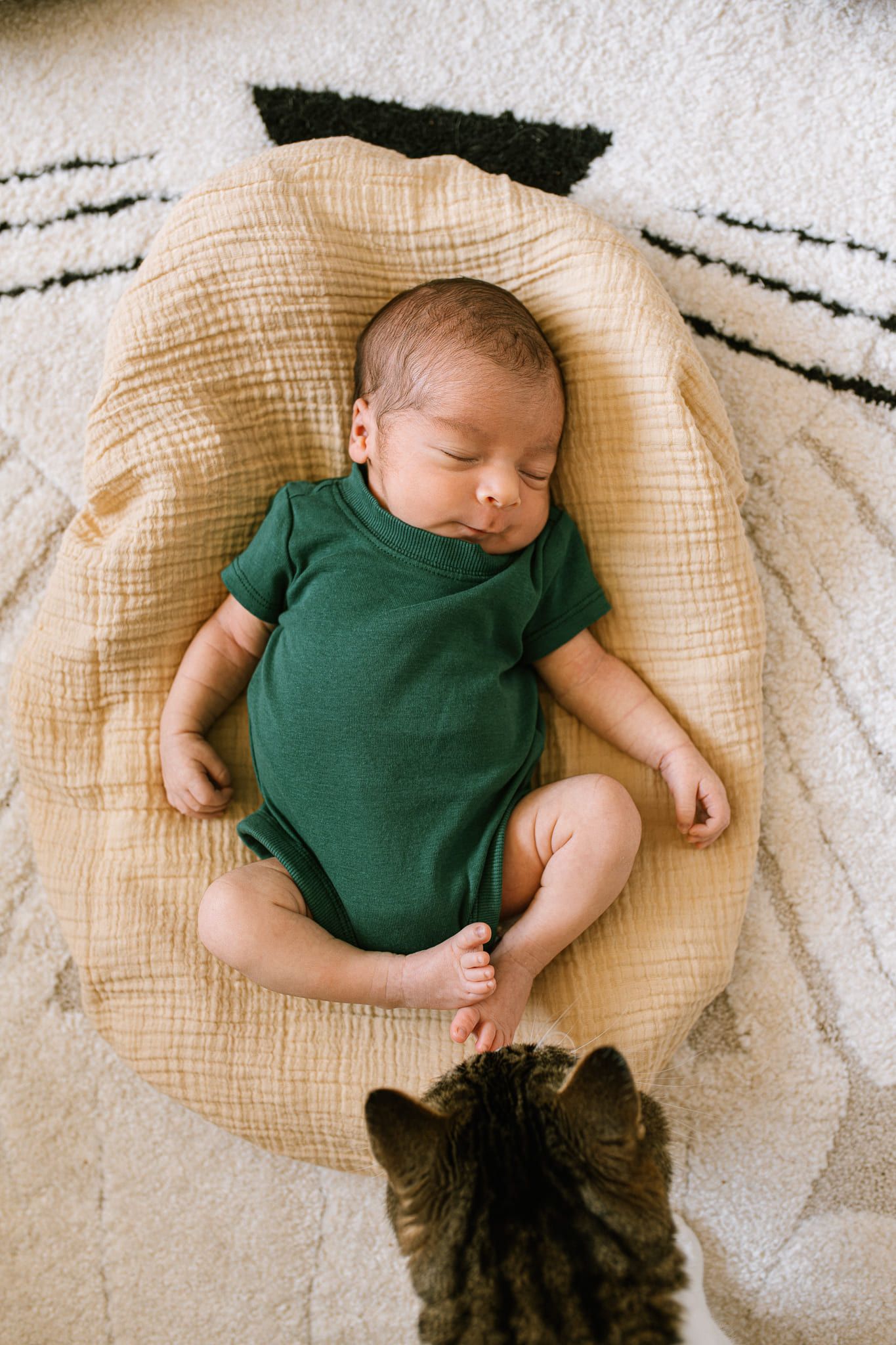 Newborn family shoot, newborn boy in a green bodysuit with his parents in their nursery